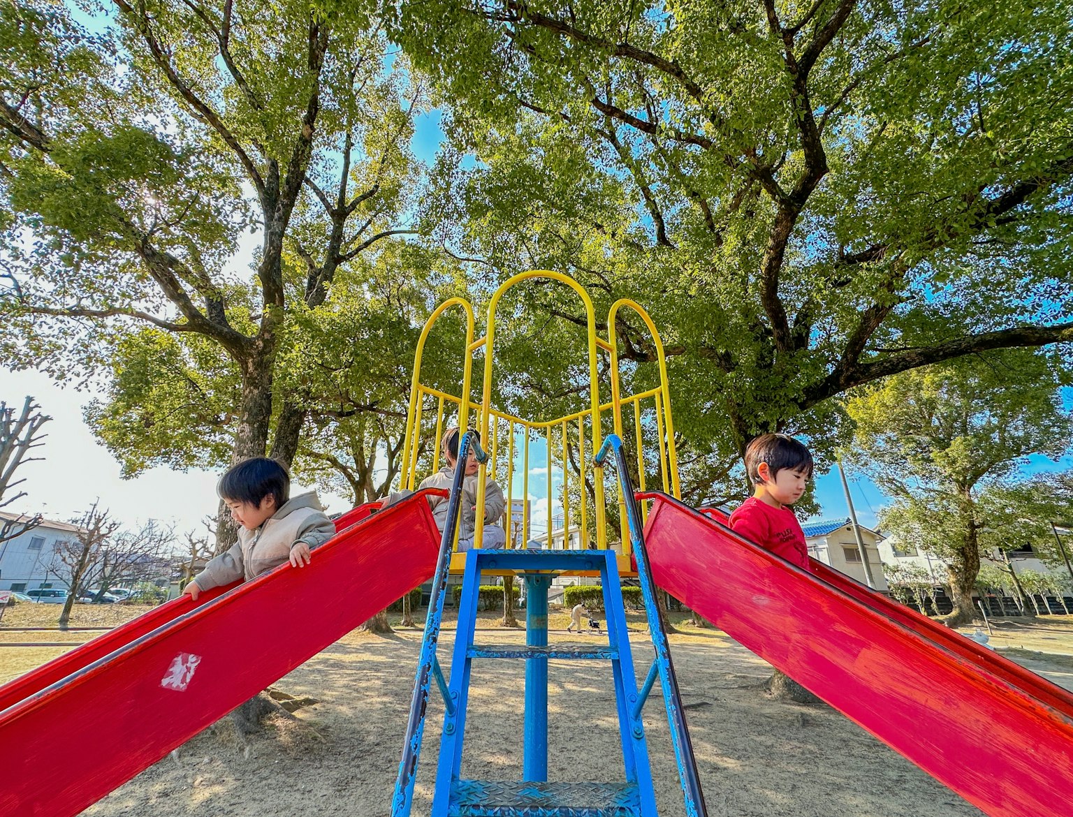 Due bambini che giocano su scivoli in un parco