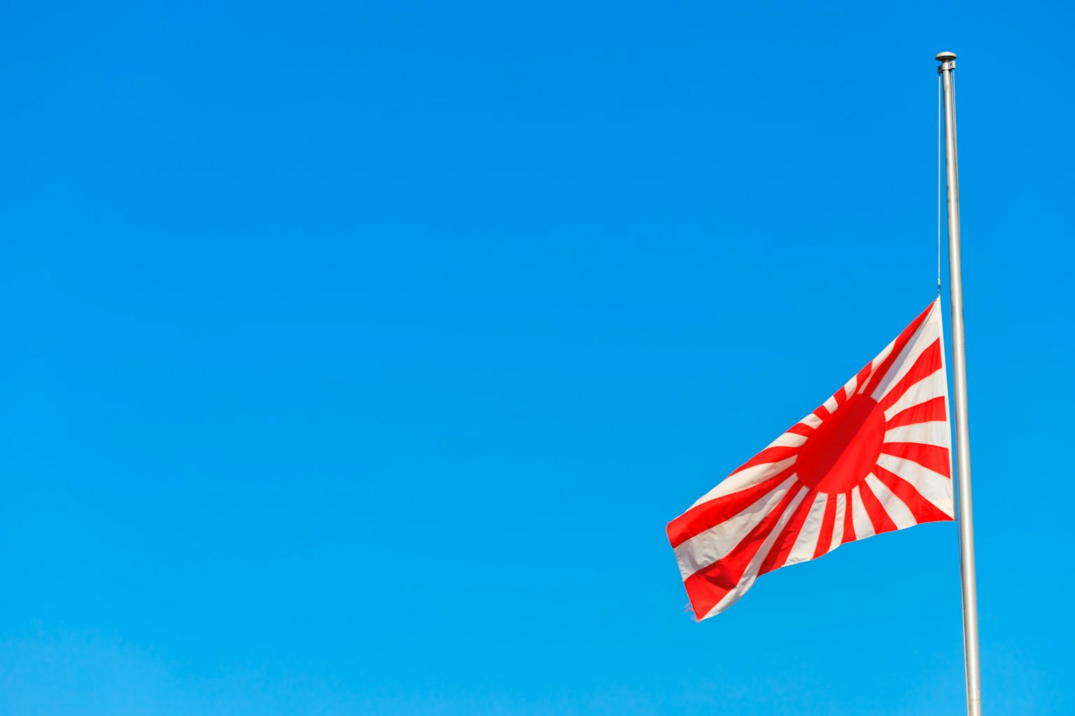 Rising sun flag displayed against a blue sky