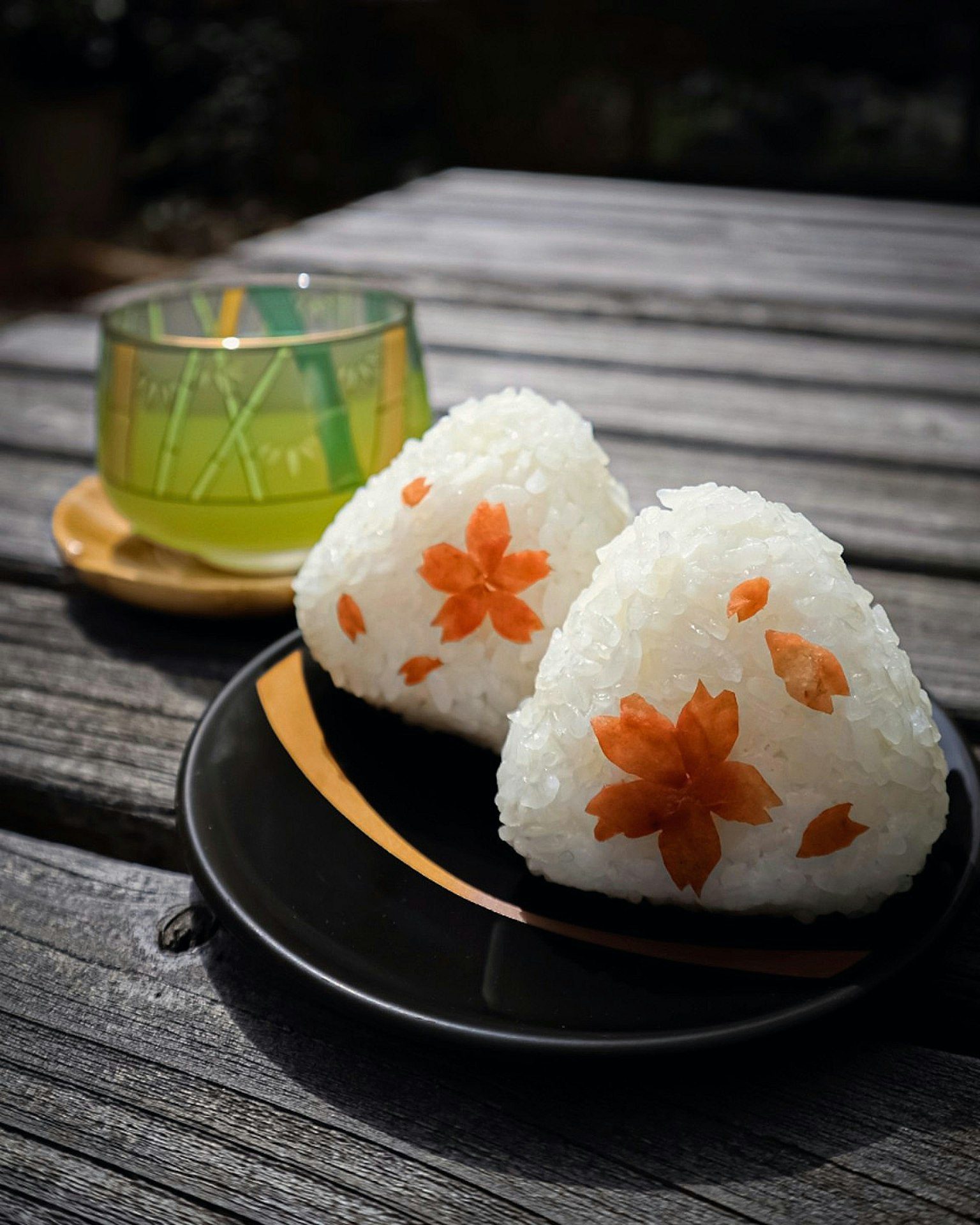 Boulettes de riz décorées de motifs de fleurs de cerisier et un verre de thé vert