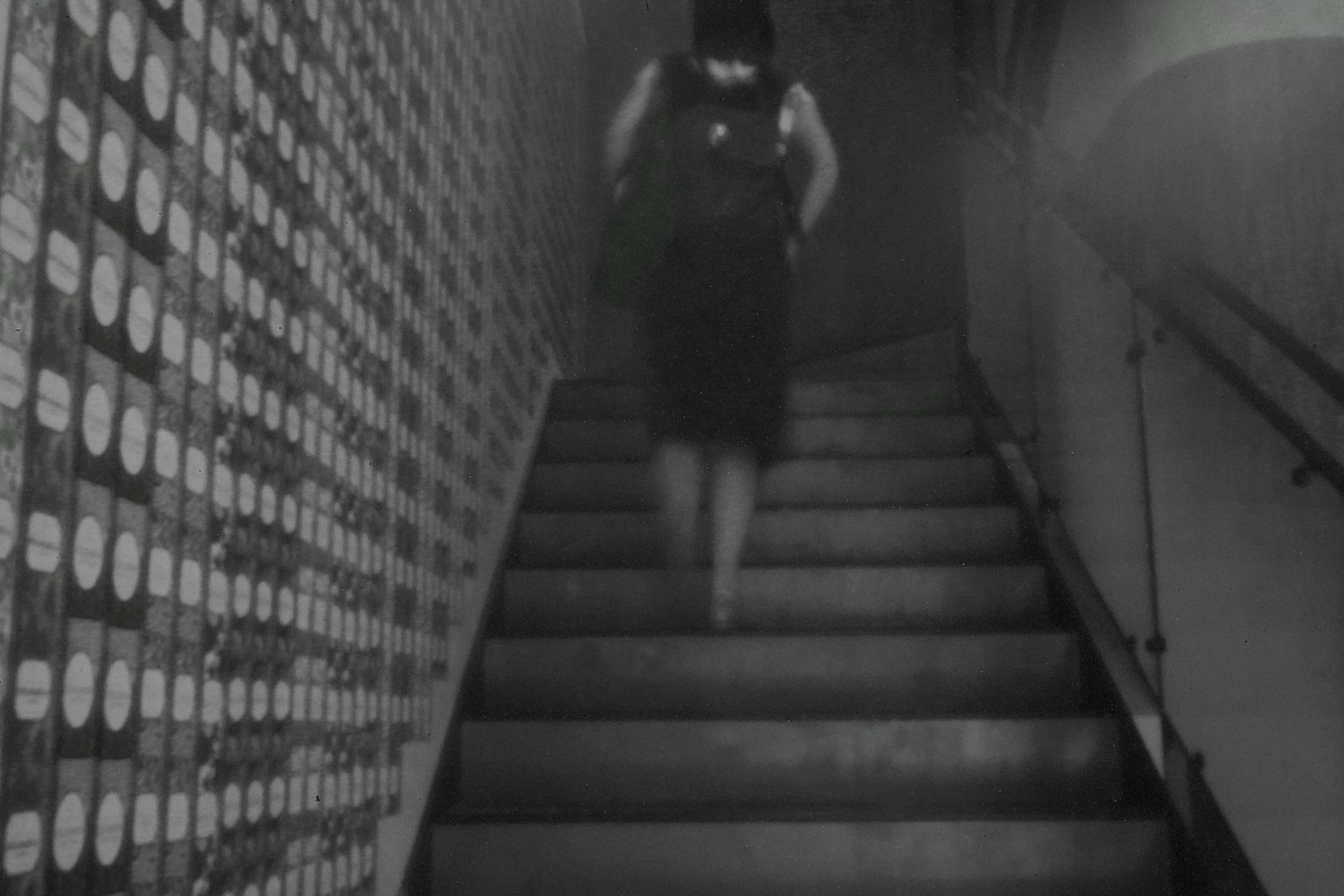 Silhouette of a woman descending stairs with a monochrome wall