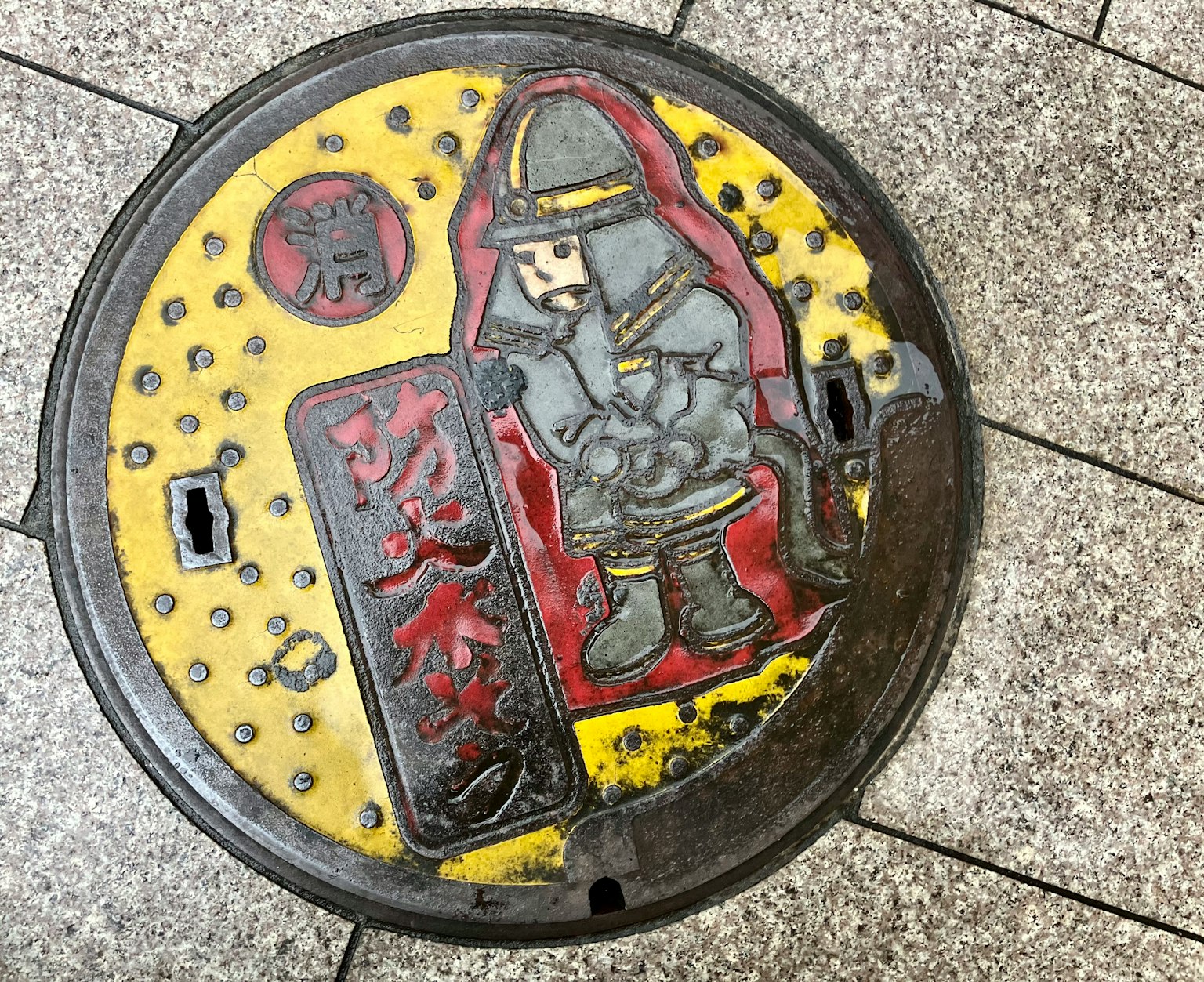 Cubierta de alcantarilla colorida con ilustración de un bombero y diseño