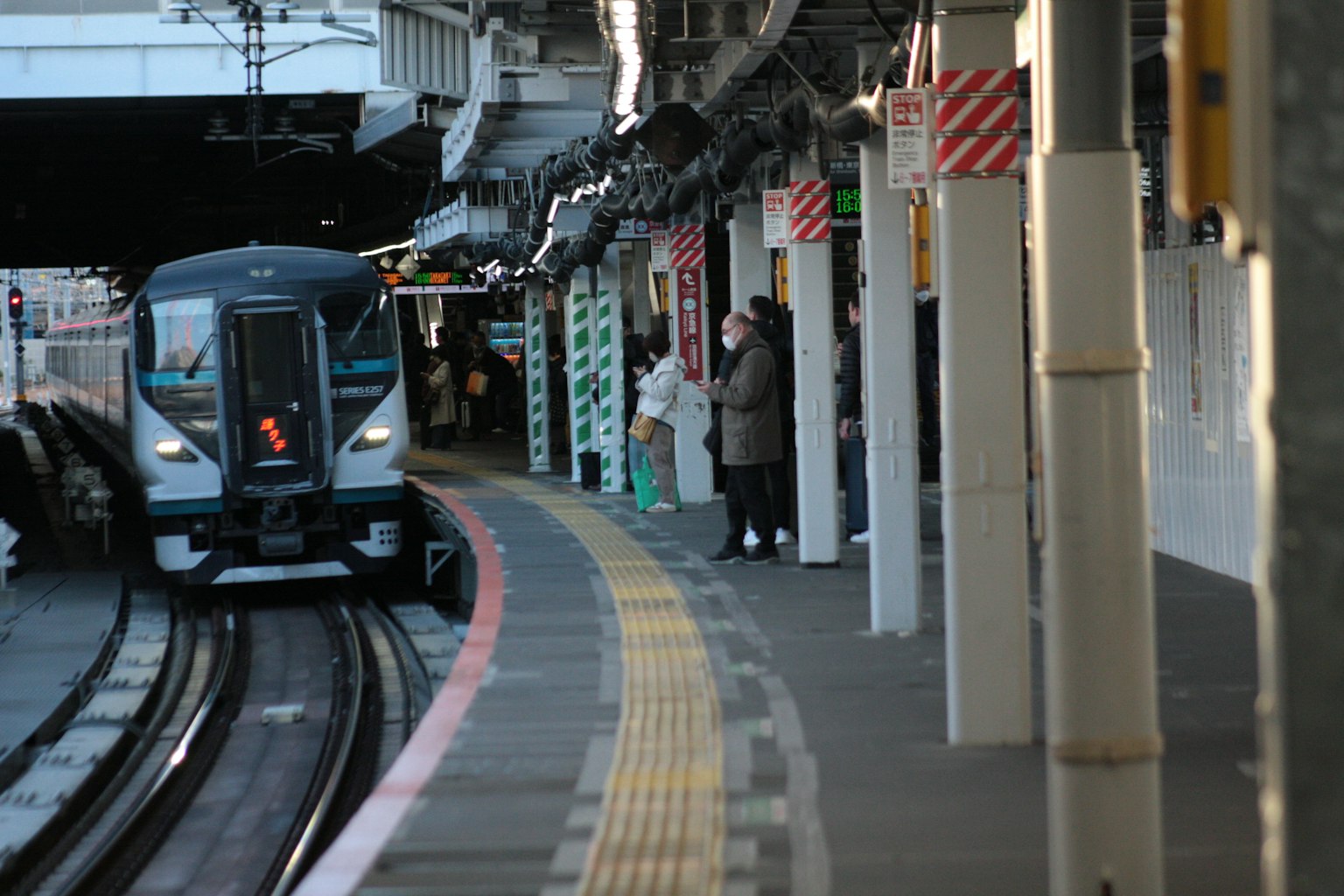 Kereta tiba di platform stasiun dengan penumpang menunggu