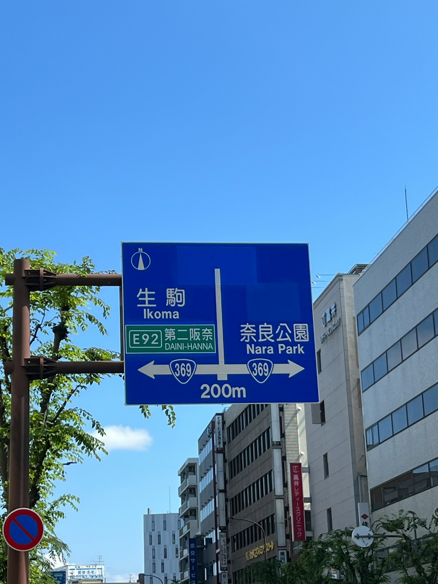 Blue road sign indicating directions to Ikuta and Shinjuku Park