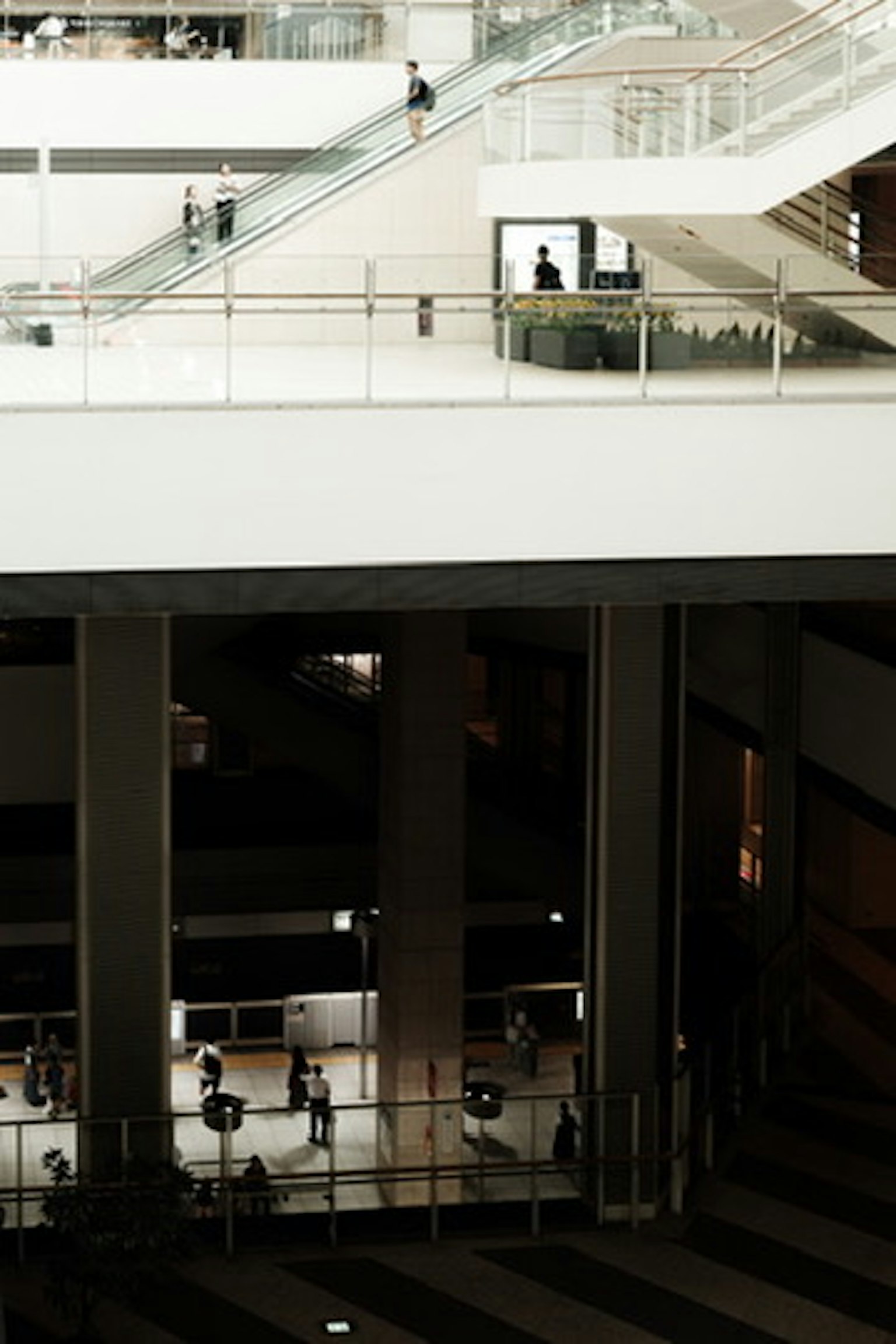 Nội thất của một tòa nhà trắng với cầu thang và người di chuyển