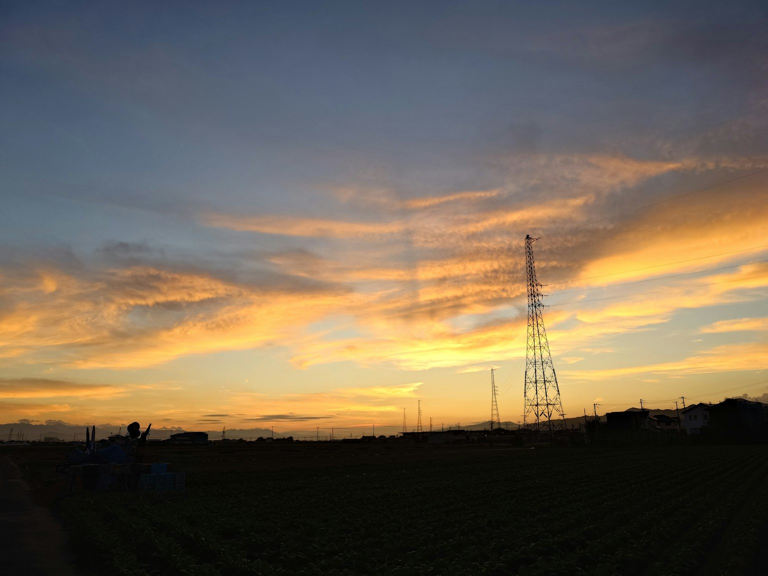 夕焼けの空に映える電波塔と広がる田園風景