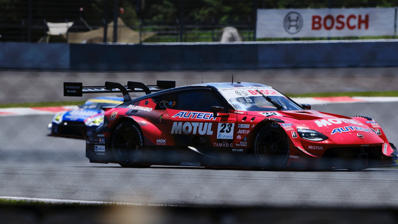 Voiture de course rouge dépassant un autre véhicule sur une piste de course