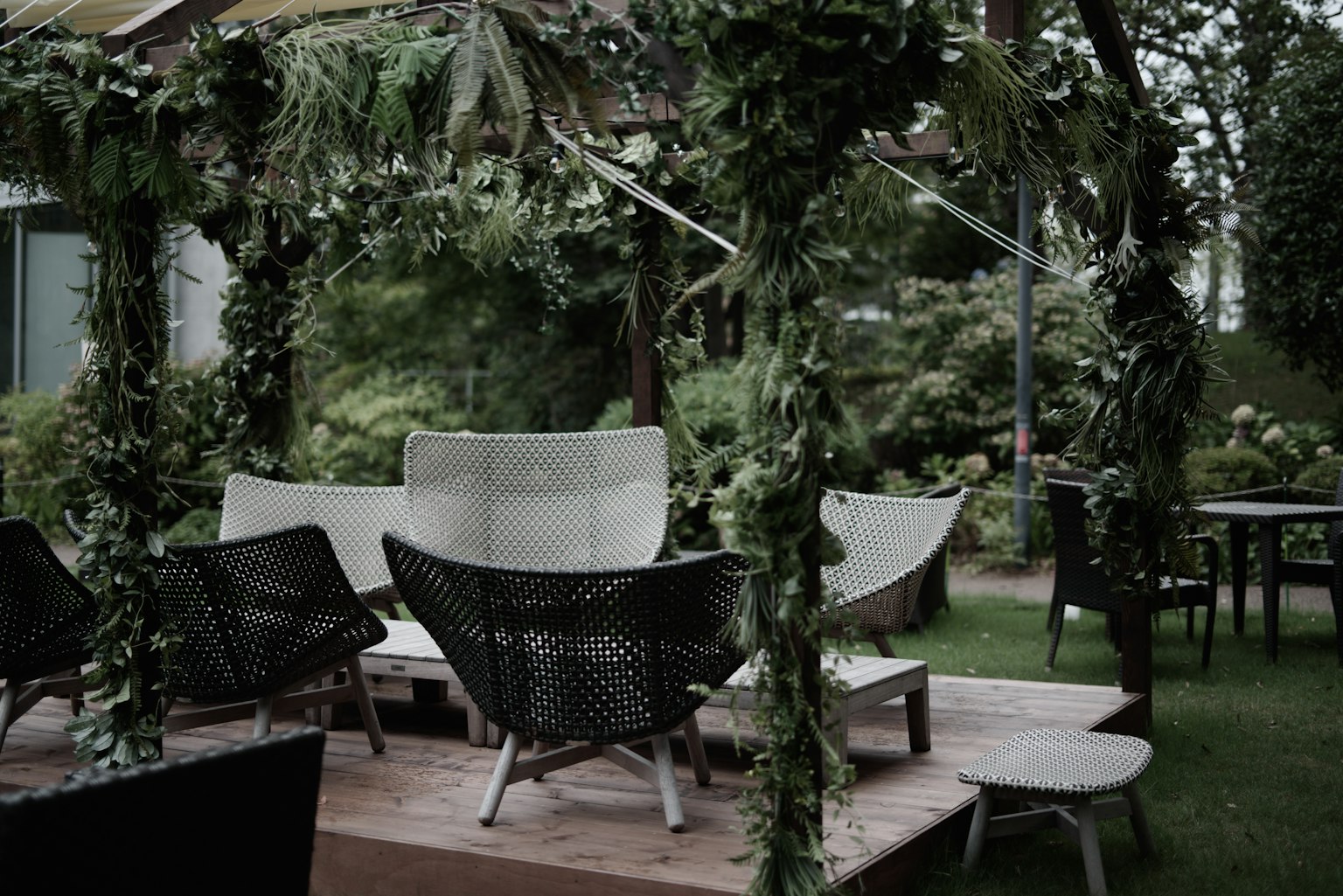 Área de salón al aire libre decorada con vegetación y sillas elegantes