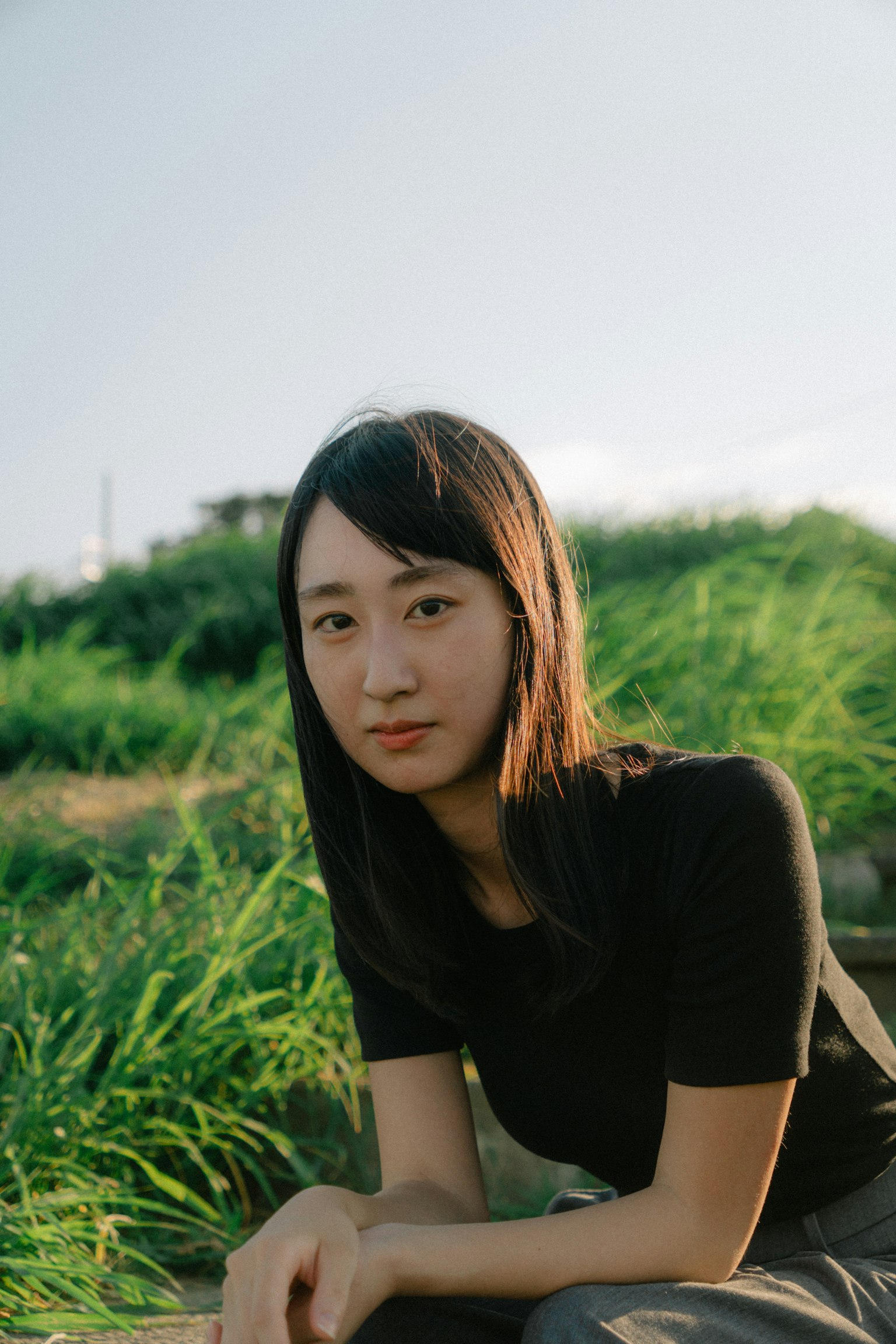 Portrait d'une femme assise devant un champ d'herbe verte