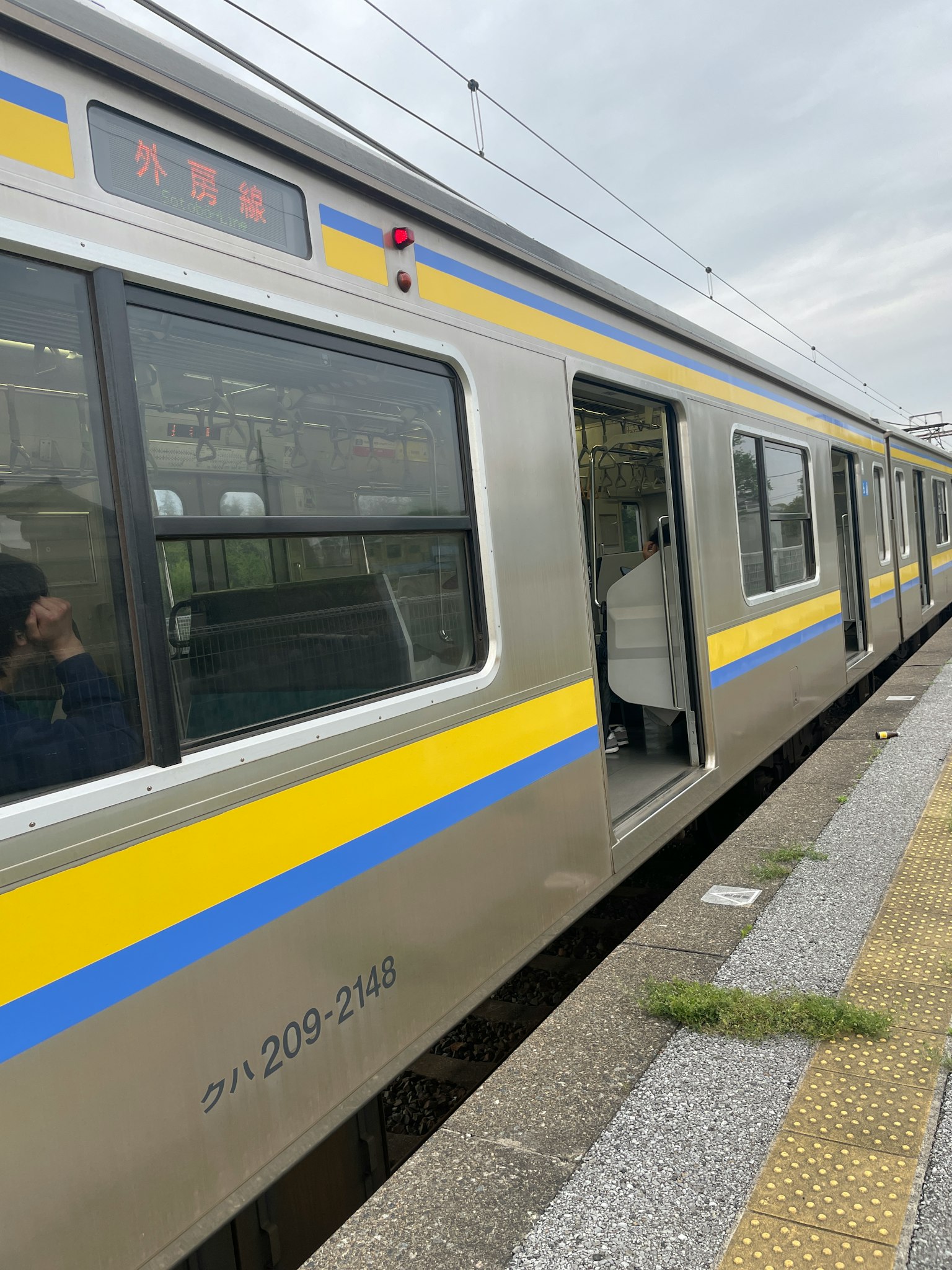 Treno argentato con strisce gialle e blu fermo a una stazione