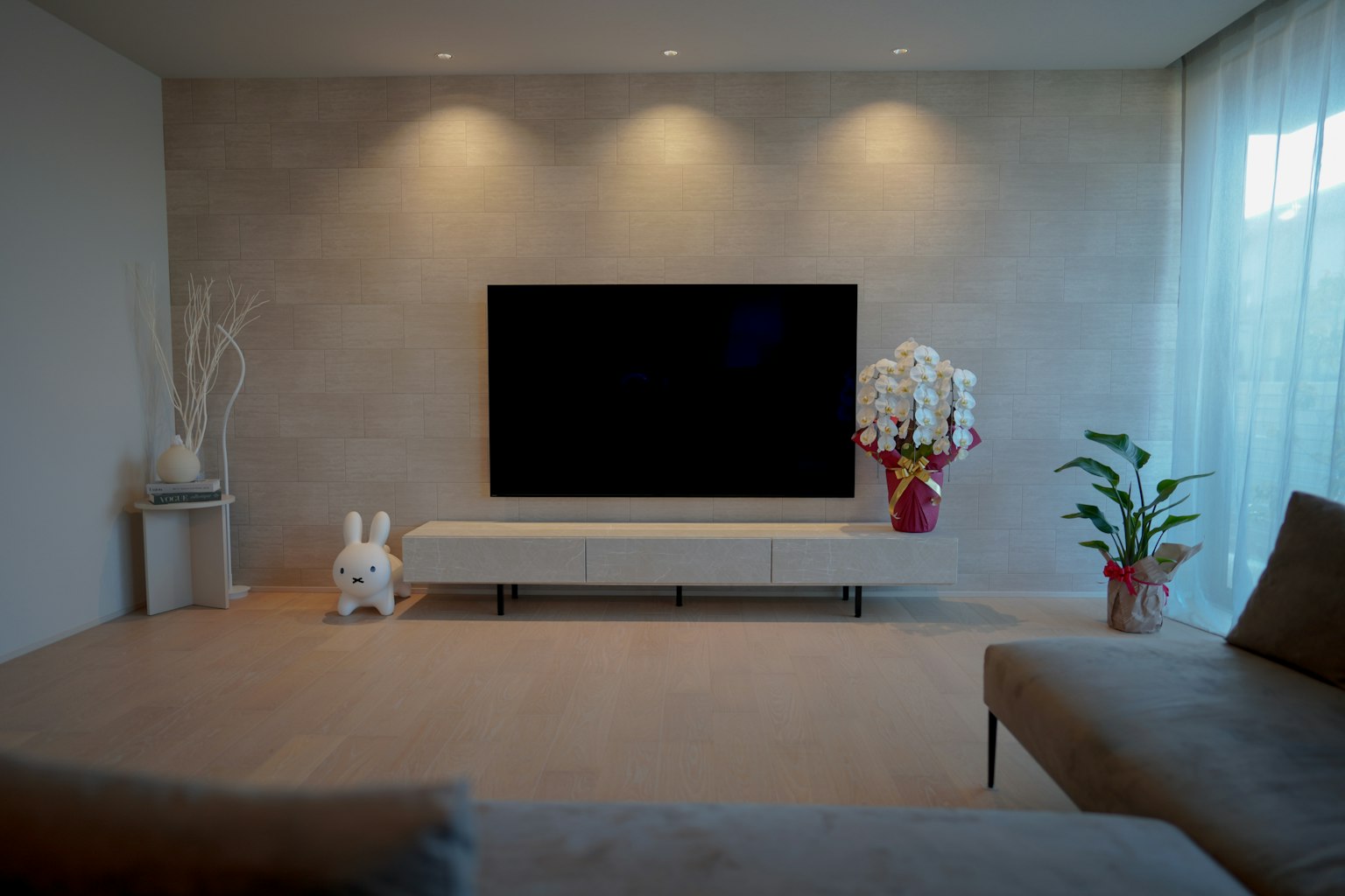 Ruang tamu modern dengan televisi besar dan furnitur putih