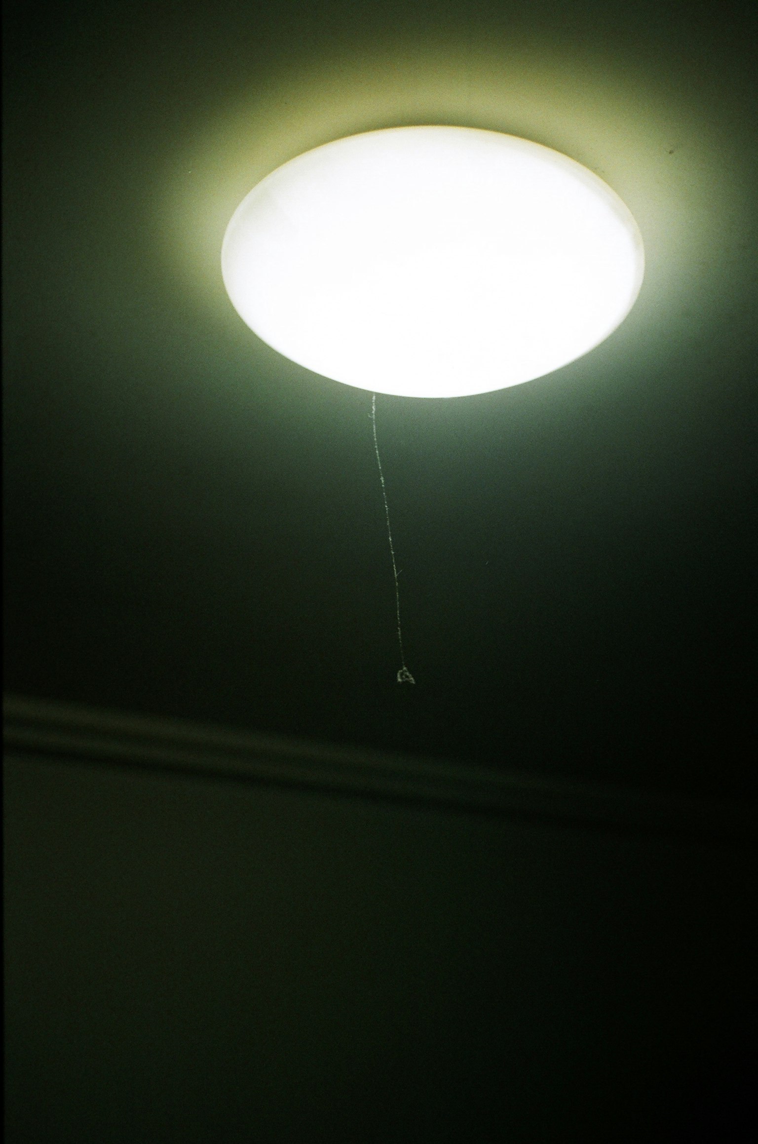 天井に取り付けられた丸い照明器具と引き紐