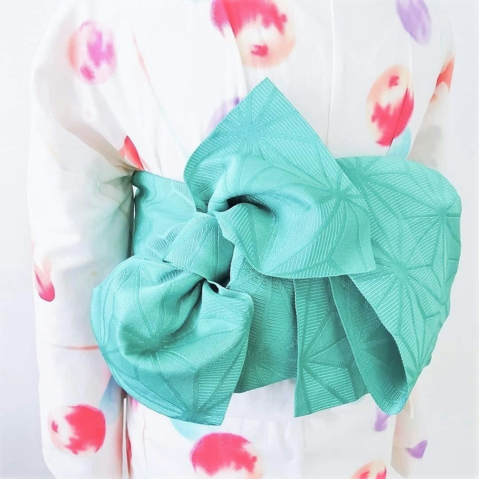 Kimono bermotif bunga berwarna-warni dengan obi biru terang diikat dengan anggun di belakang