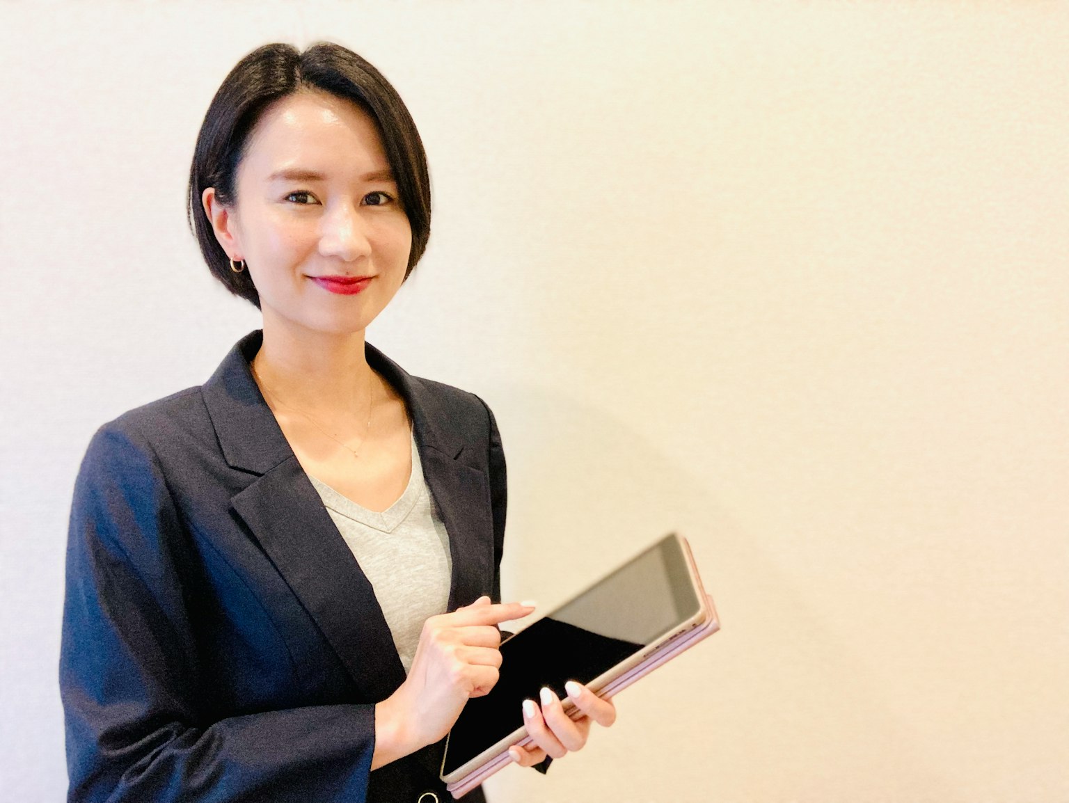 Eine Frau im Business-Anzug, die ein Tablet hält und lächelt