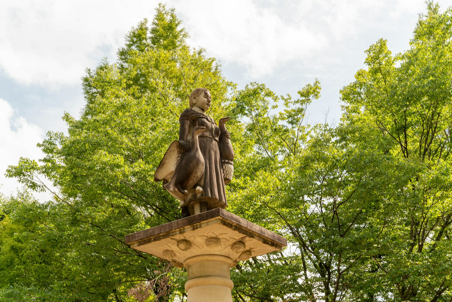 Statua su un piedistallo circondata da alberi verdi