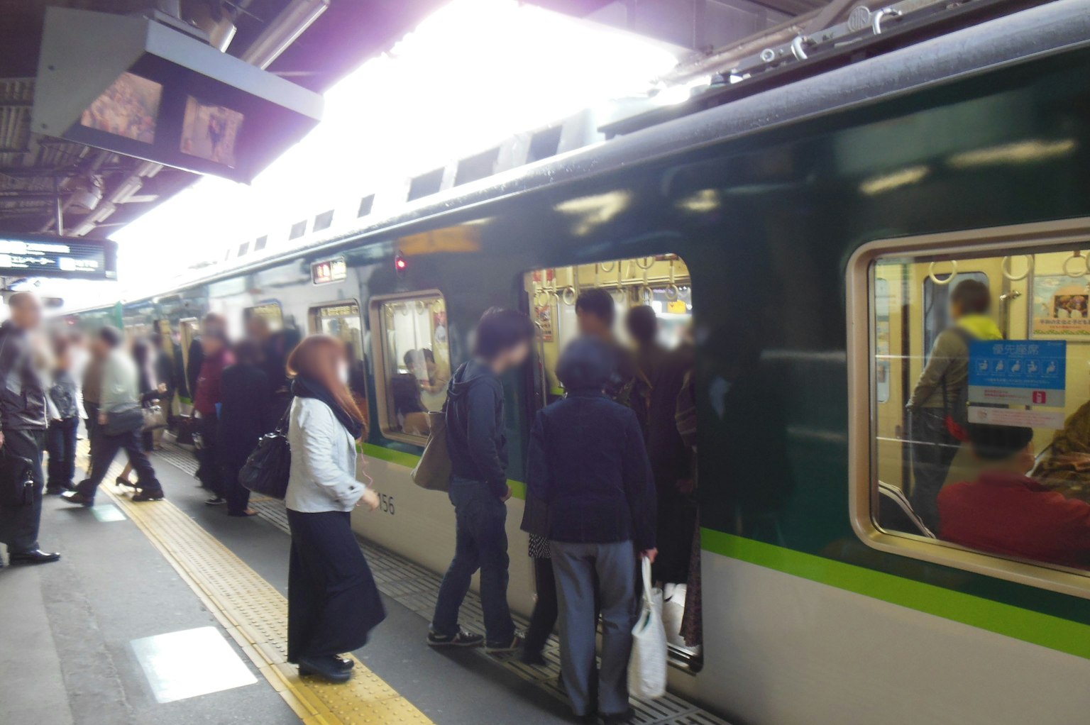 Estación concurrida con personas subiendo a un tren verde