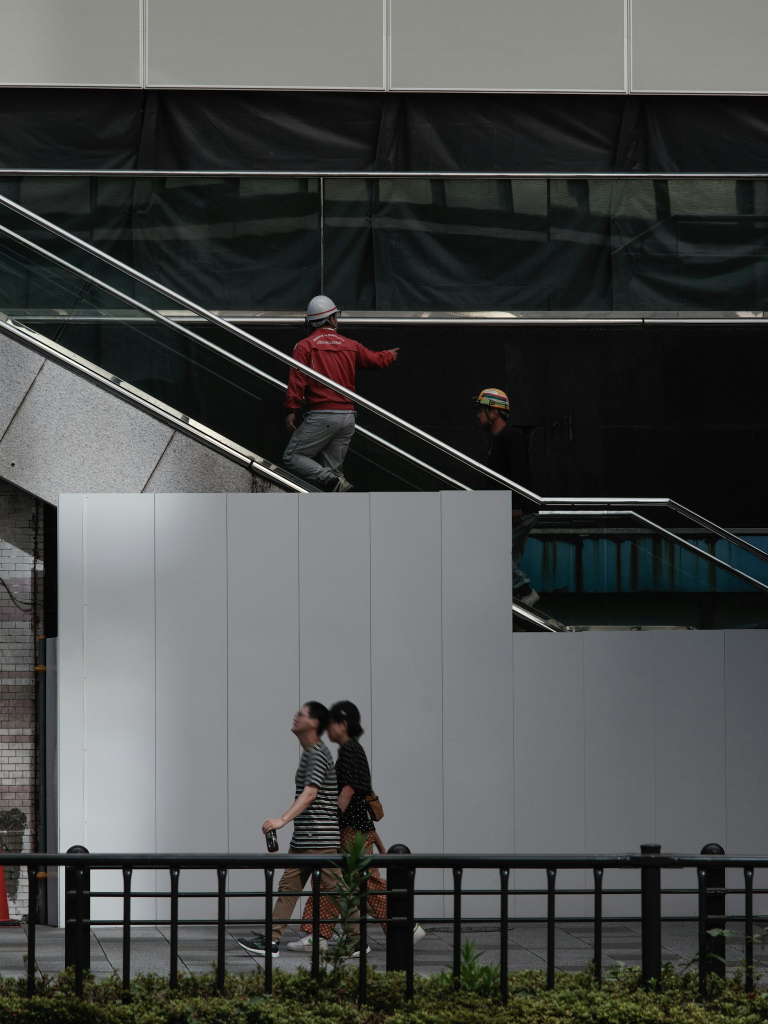 Image of a man in red going up stairs and two women walking