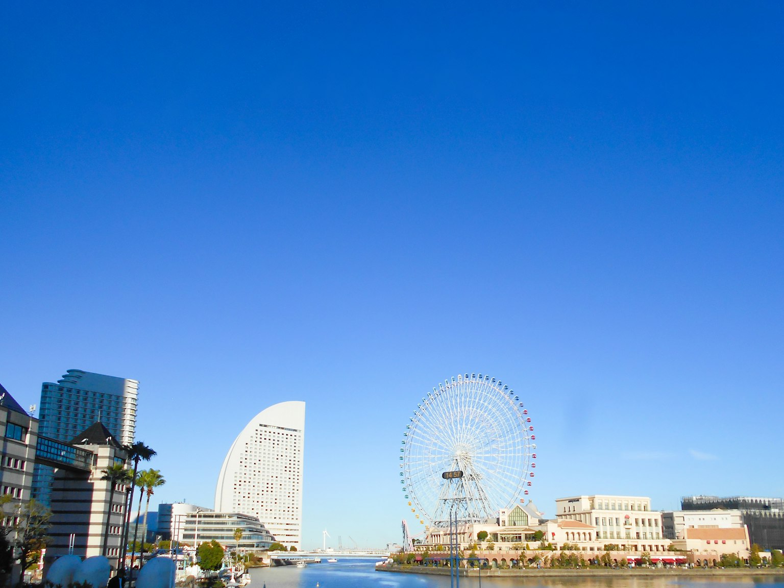 Skyline von Yokohama mit Hochhäusern und einem Riesenrad unter einem klaren blauen Himmel