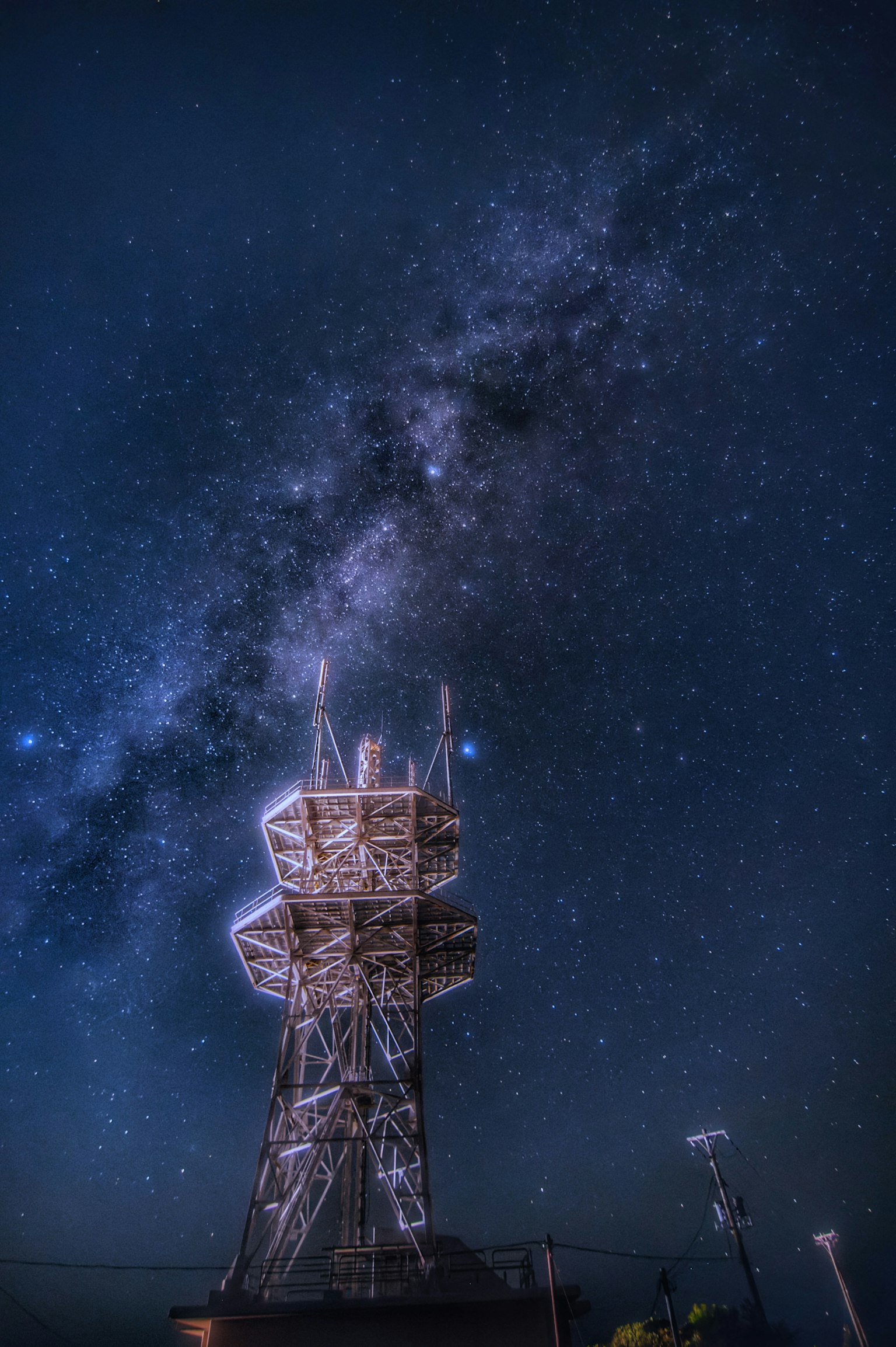Hermosa vista de la Vía Láctea brillando en el cielo nocturno con una torre de comunicación