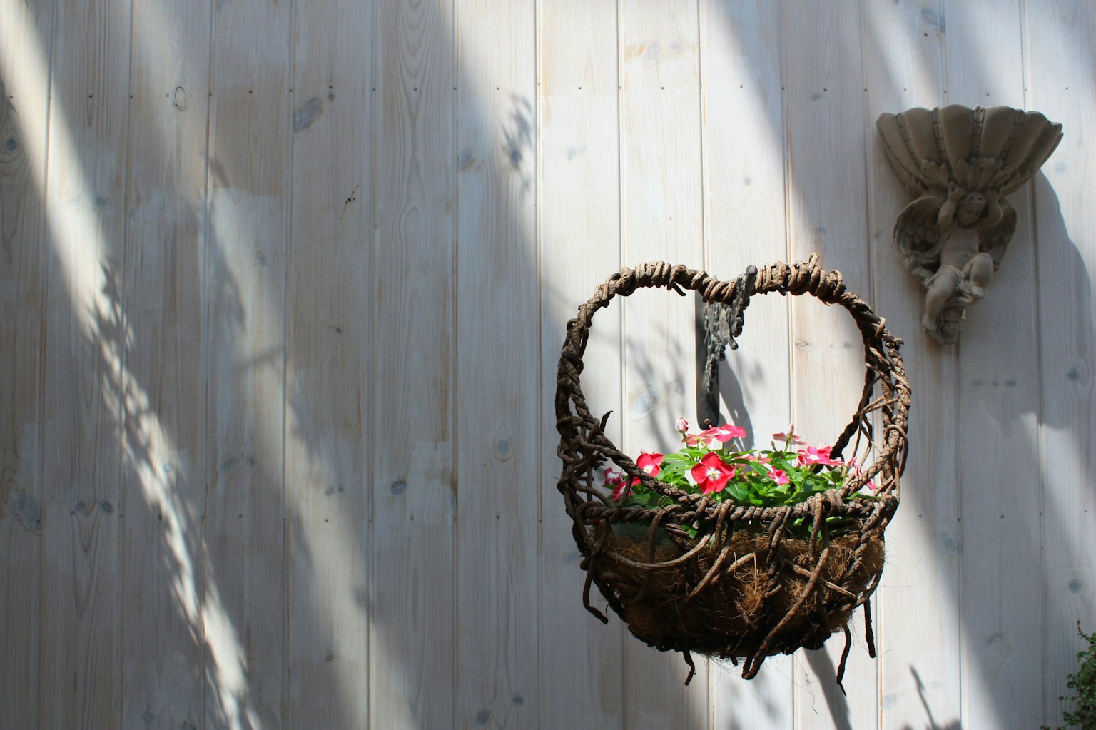 Panier de fleurs suspendu sur un mur en bois avec lumière du soleil