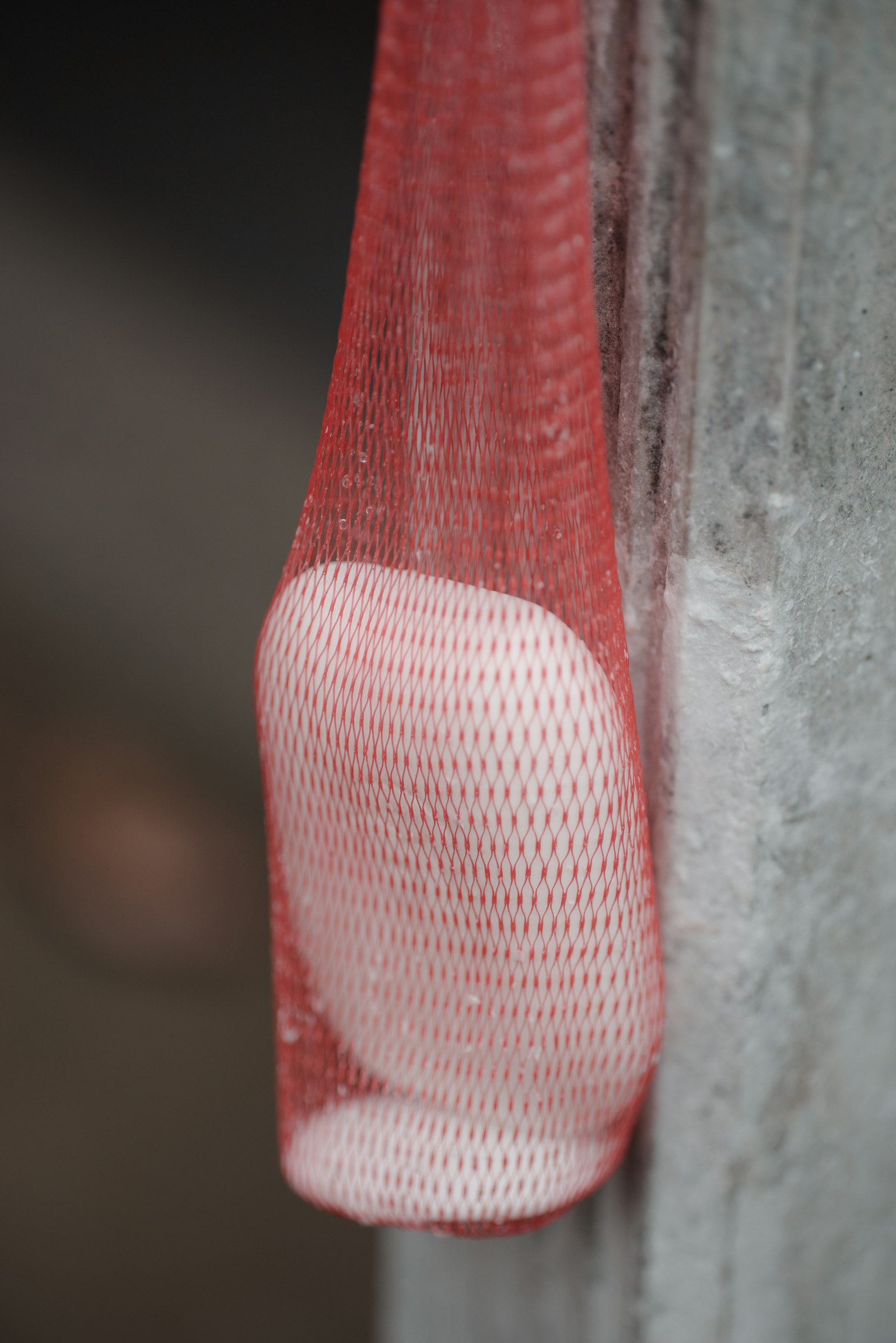 Ein weißes Objekt, das in einem roten Netz an einer Wand hängt