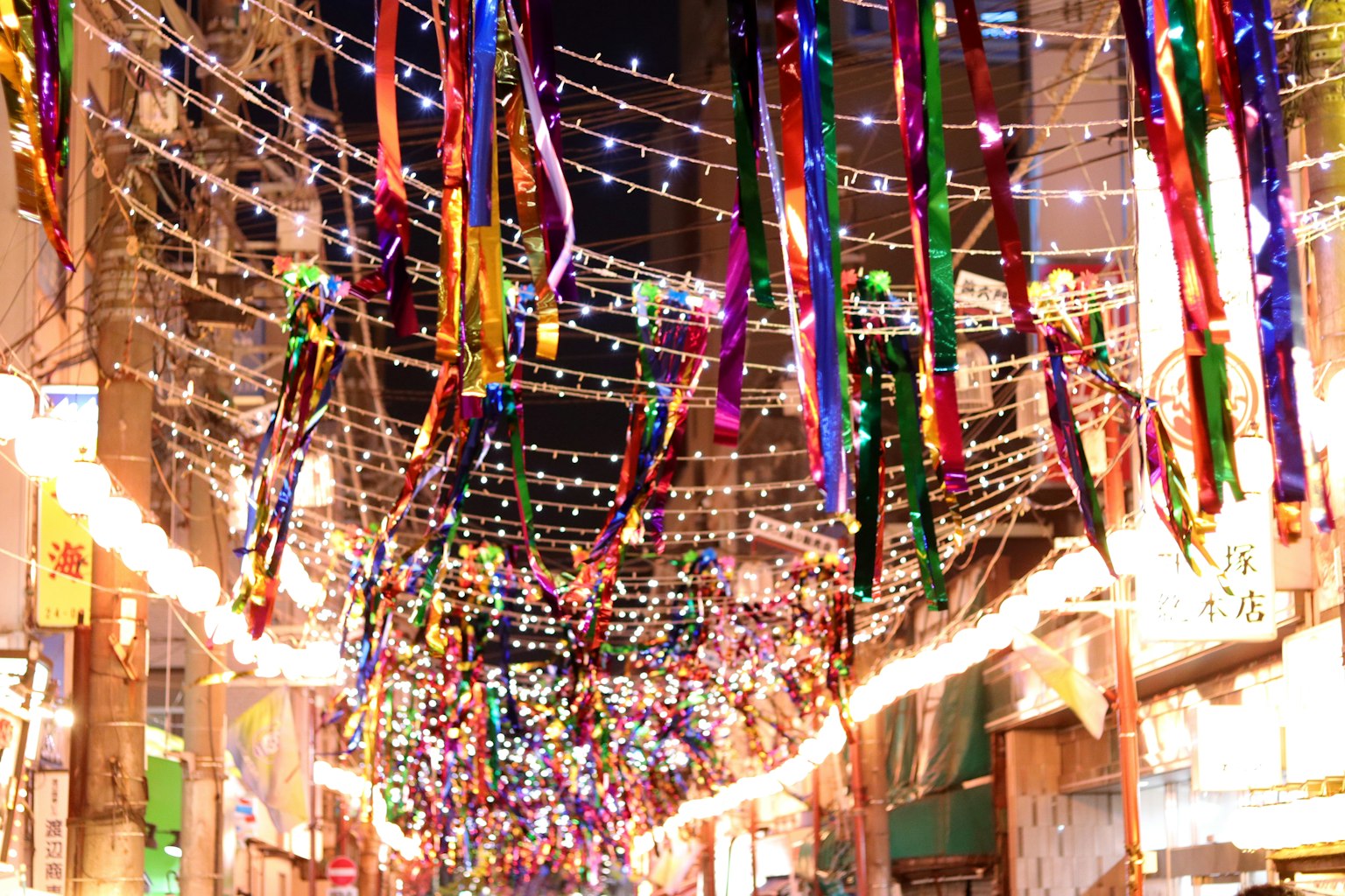 Colorful ribbons and lights hanging in a decorated street during a night festival
