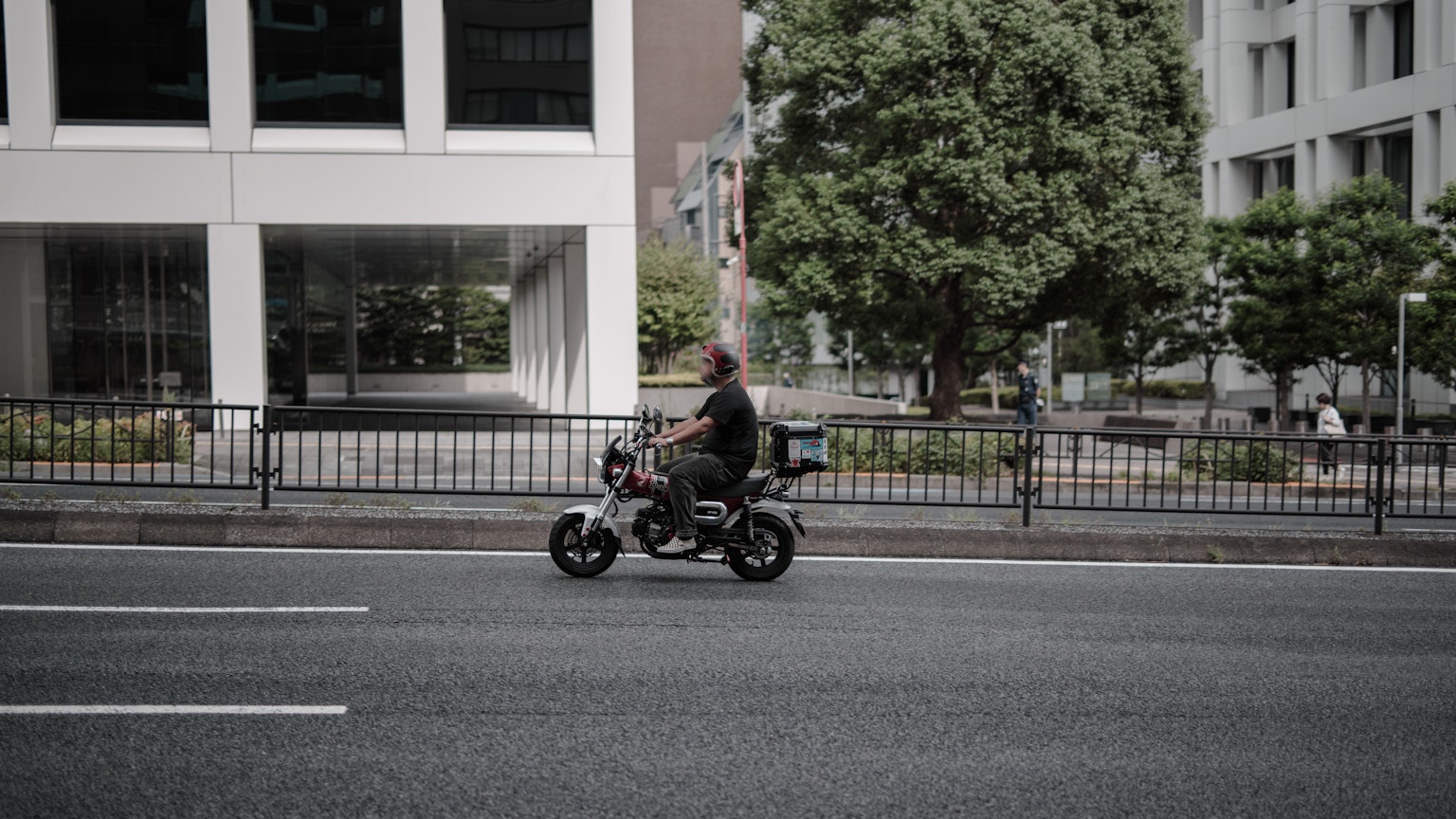 Một người đàn ông đi xe máy qua một tòa nhà hiện đại