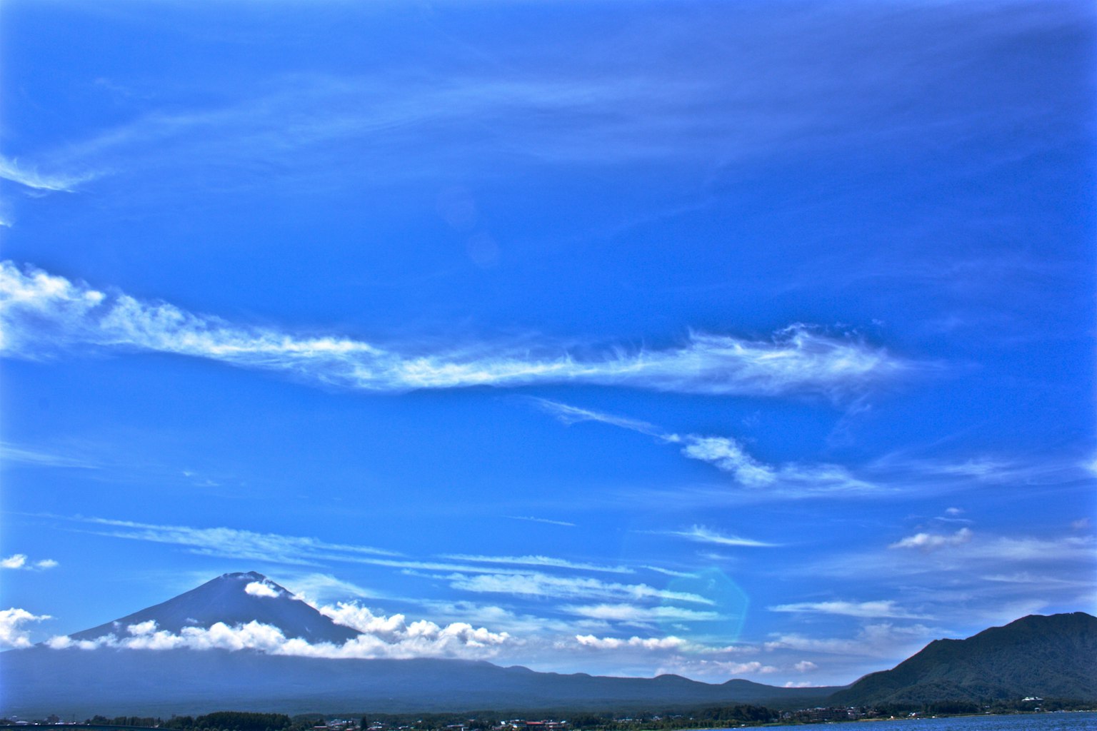 Un paisaje con cielo azul y nubes y una montaña
