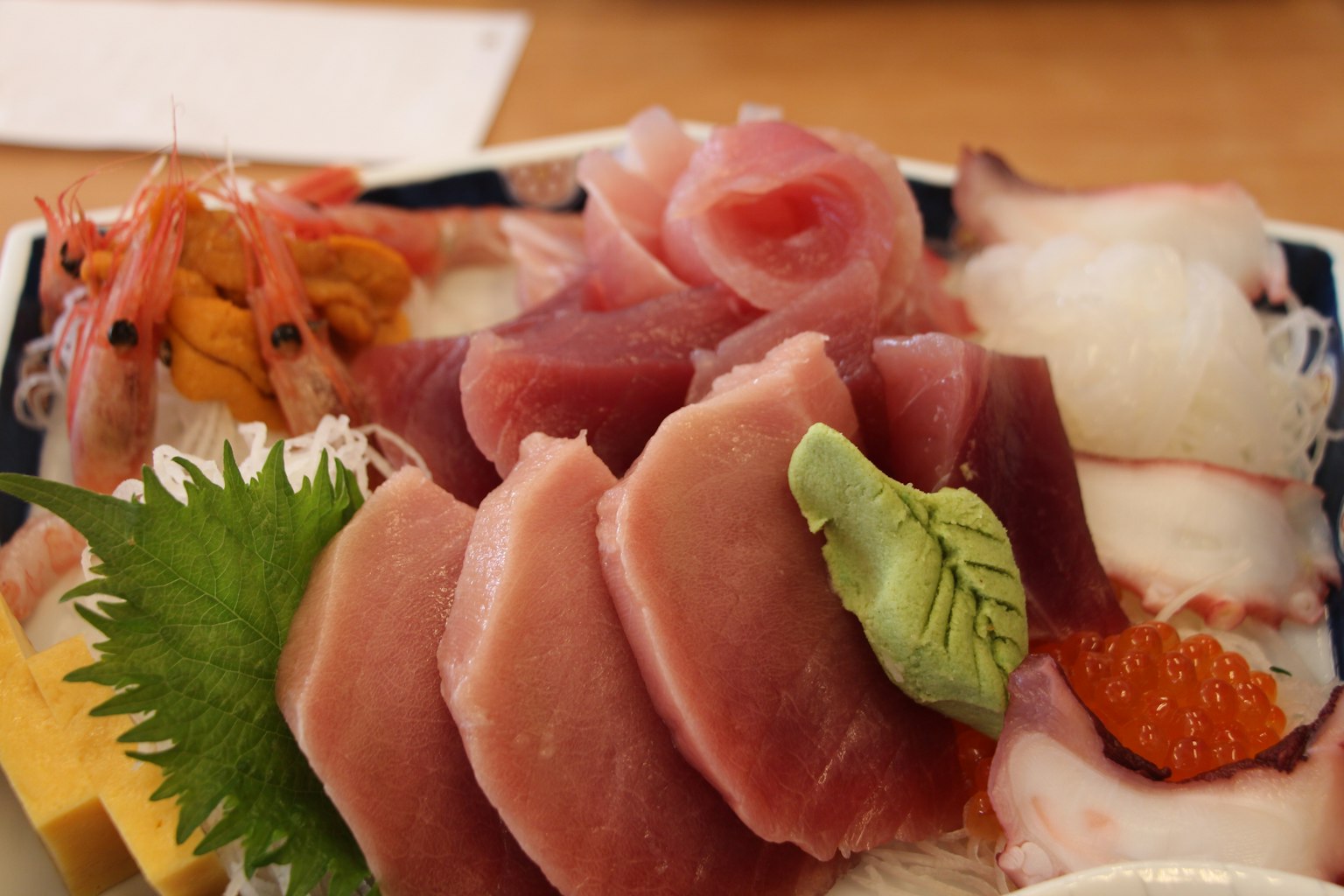 Piring sashimi segar yang mencakup tuna udang cumi dan wasabi