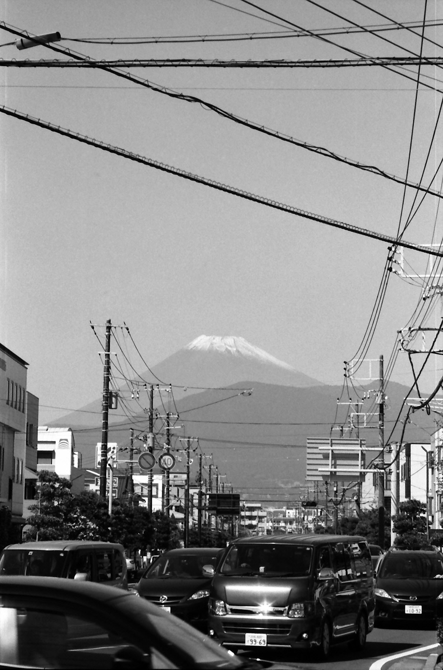 Urban landscape with Mount Fuji in the background cars on the road power lines overhead