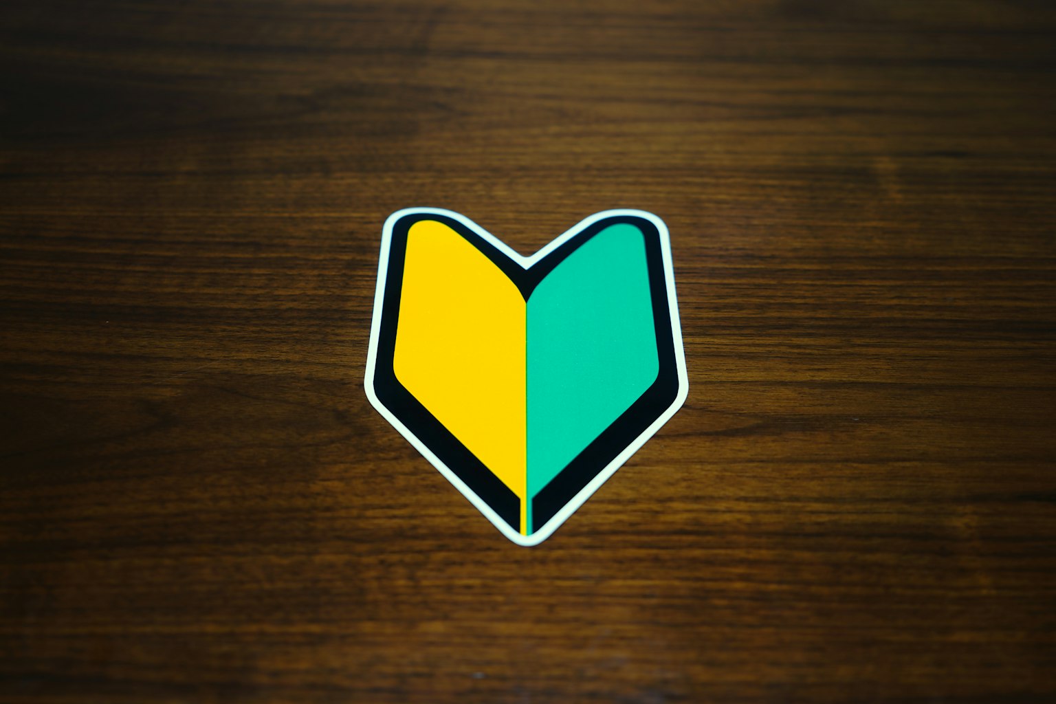 Logo en forme de cœur jaune et vert sur un fond en bois