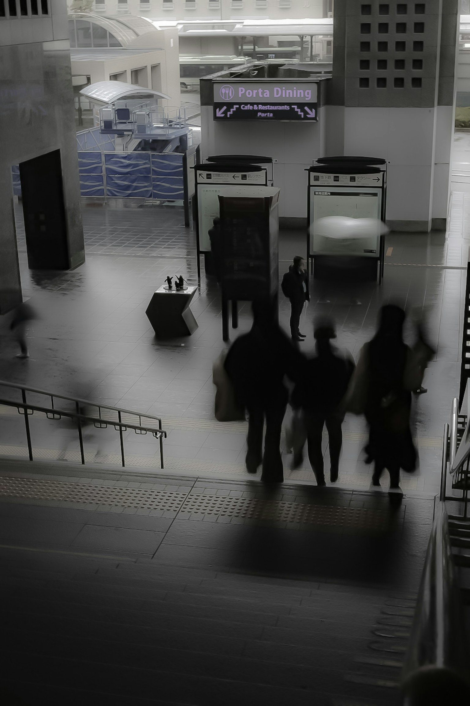 Des personnes marchant dans un intérieur de bâtiment moderne faiblement éclairé