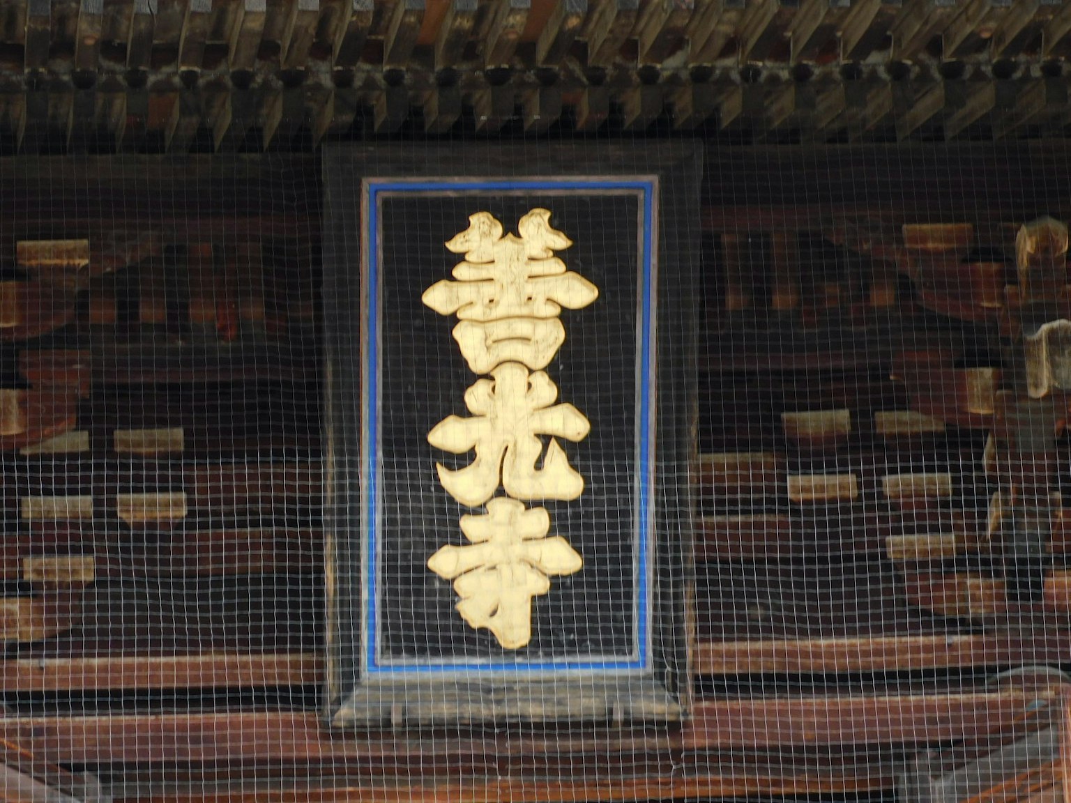 古老寺庙入口处的黑色标志，上面有金色字符
