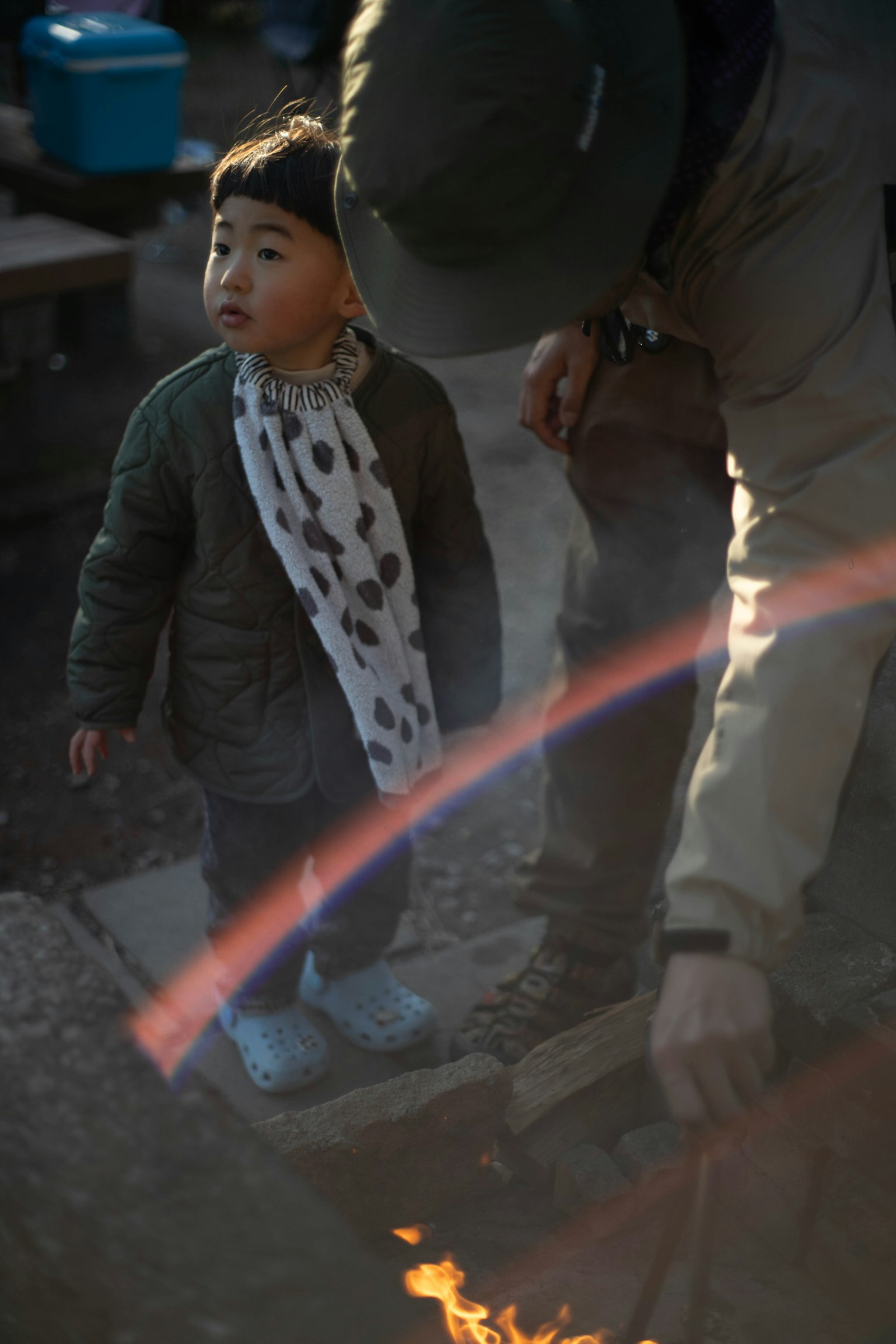 Anak berdiri di dekat api unggun dengan orang dewasa