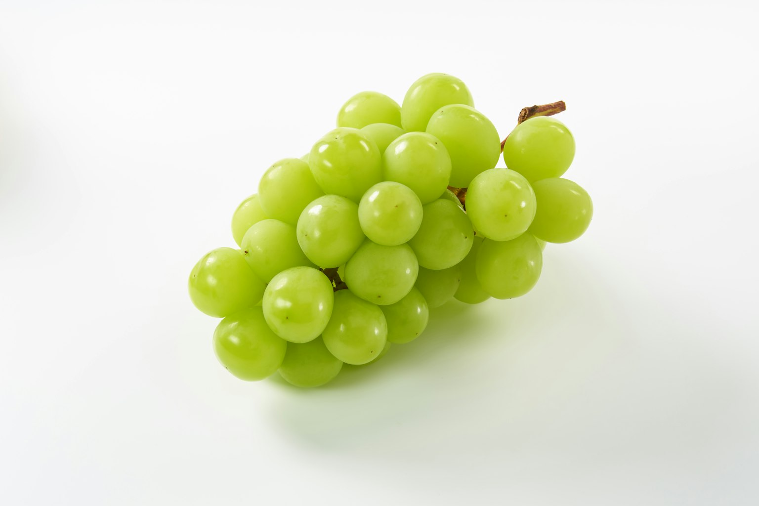 Un racimo de uvas verdes sobre un fondo blanco