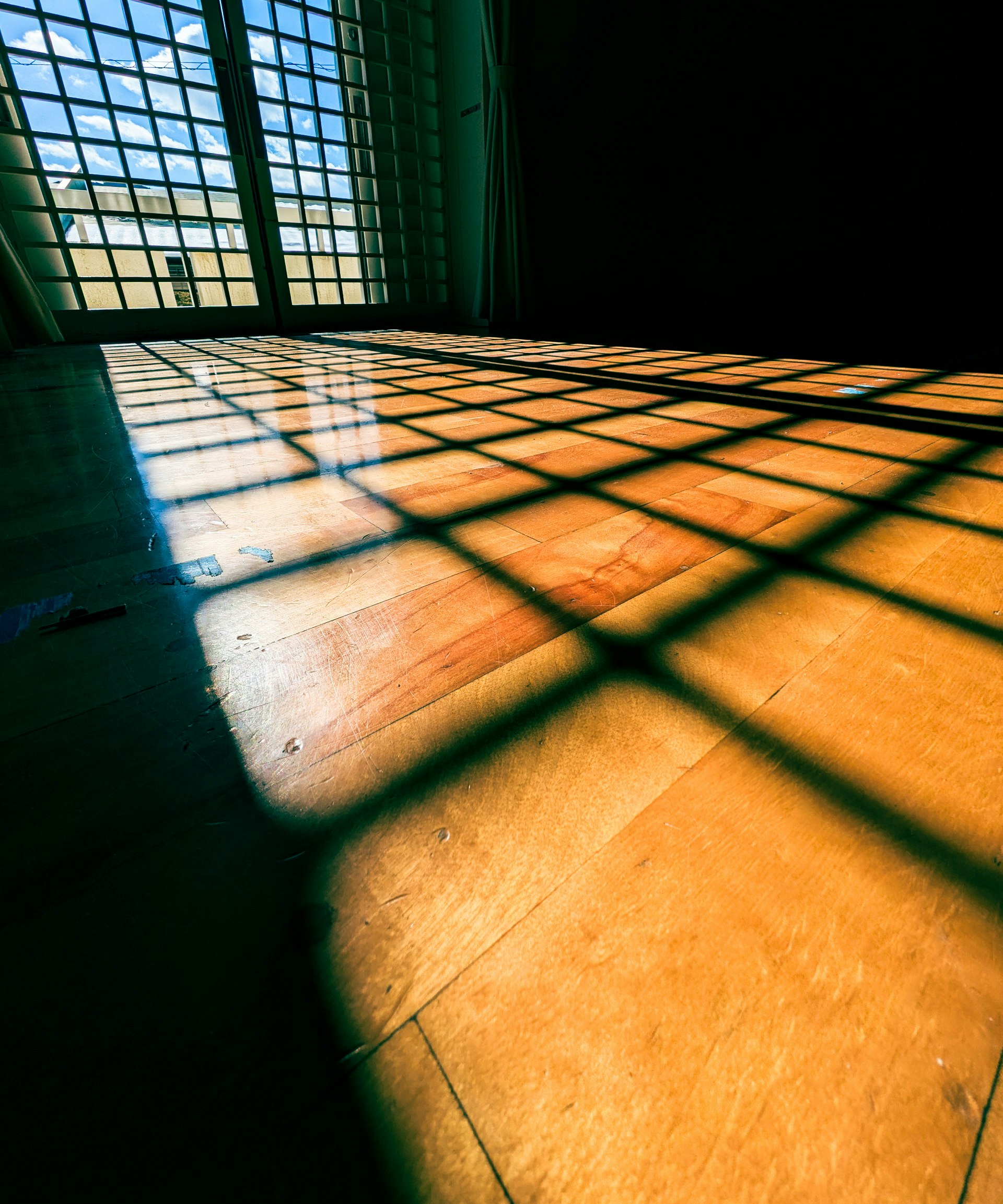 innenliegender Boden im Sonnenlicht mit Schatten eines Gitternfensters