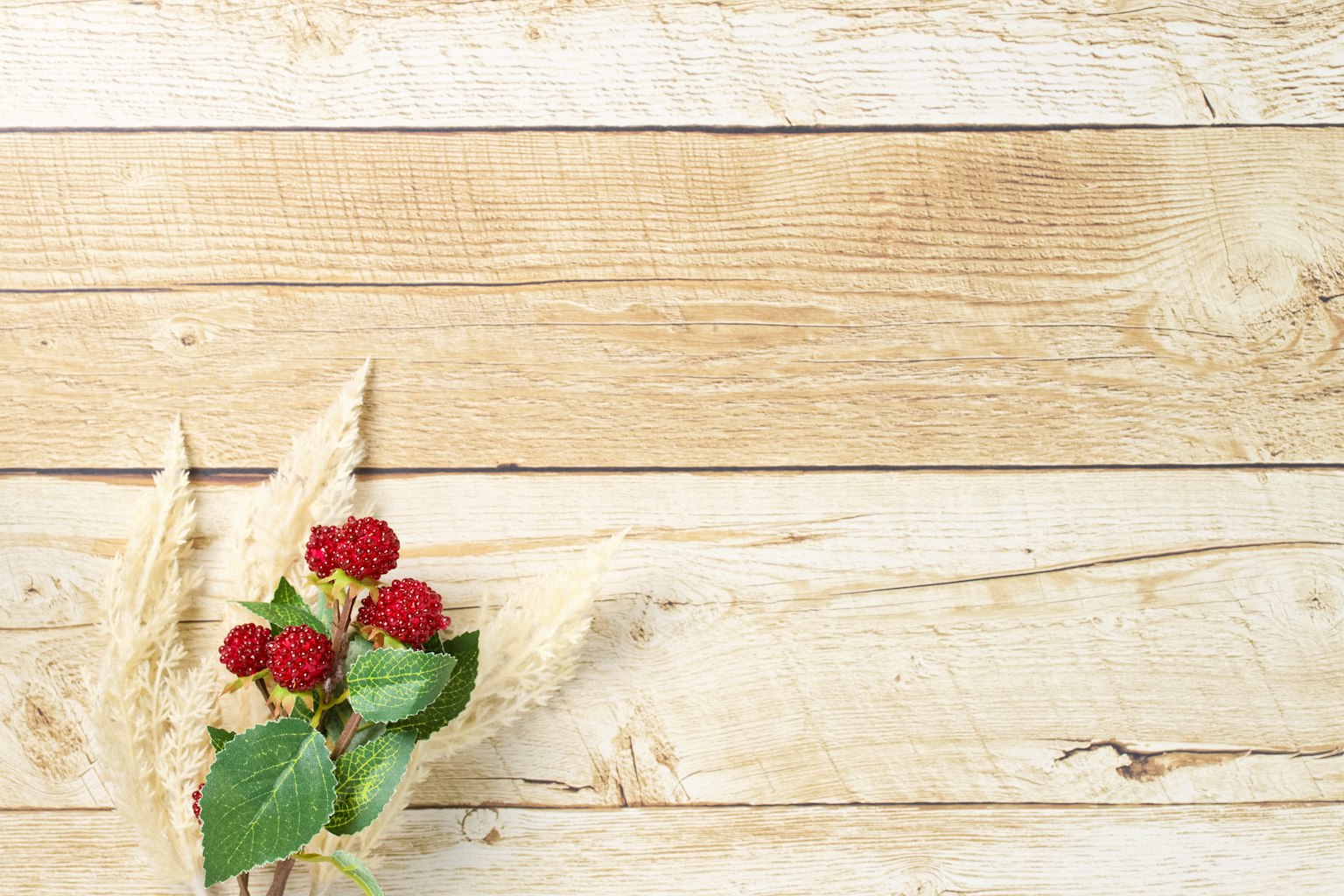 Flores rojas y hierba sobre un fondo de madera