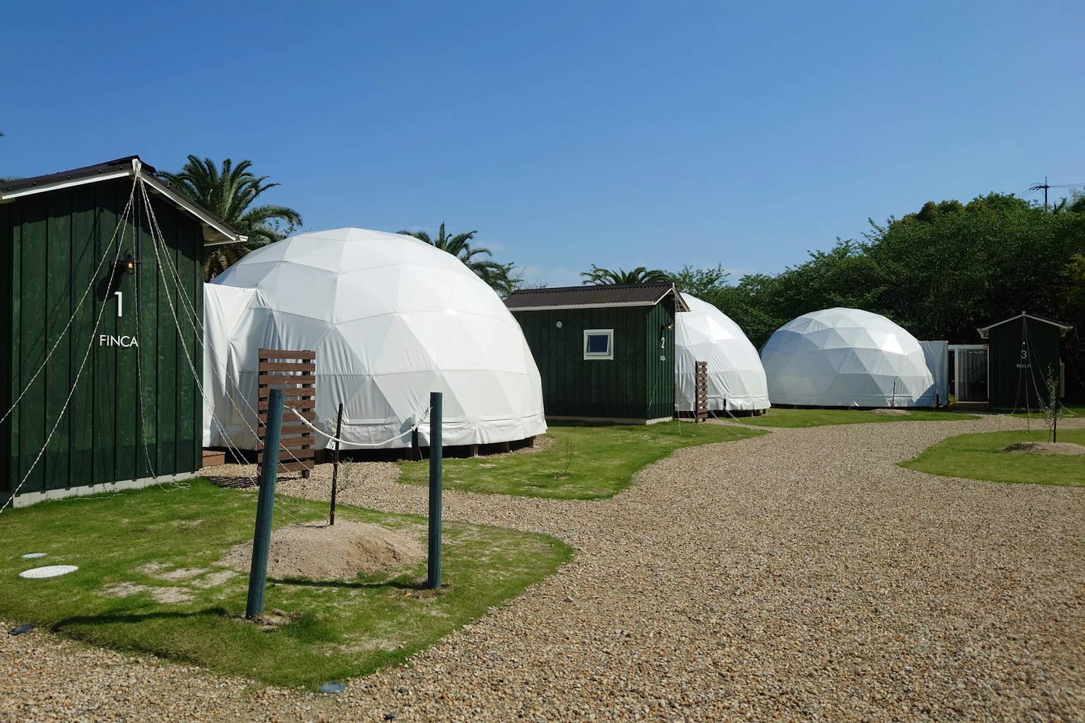 แถวของโครงสร้างโดมสีขาวพร้อมกระท่อมสีเขียวและท้องฟ้าสีฟ้าใส