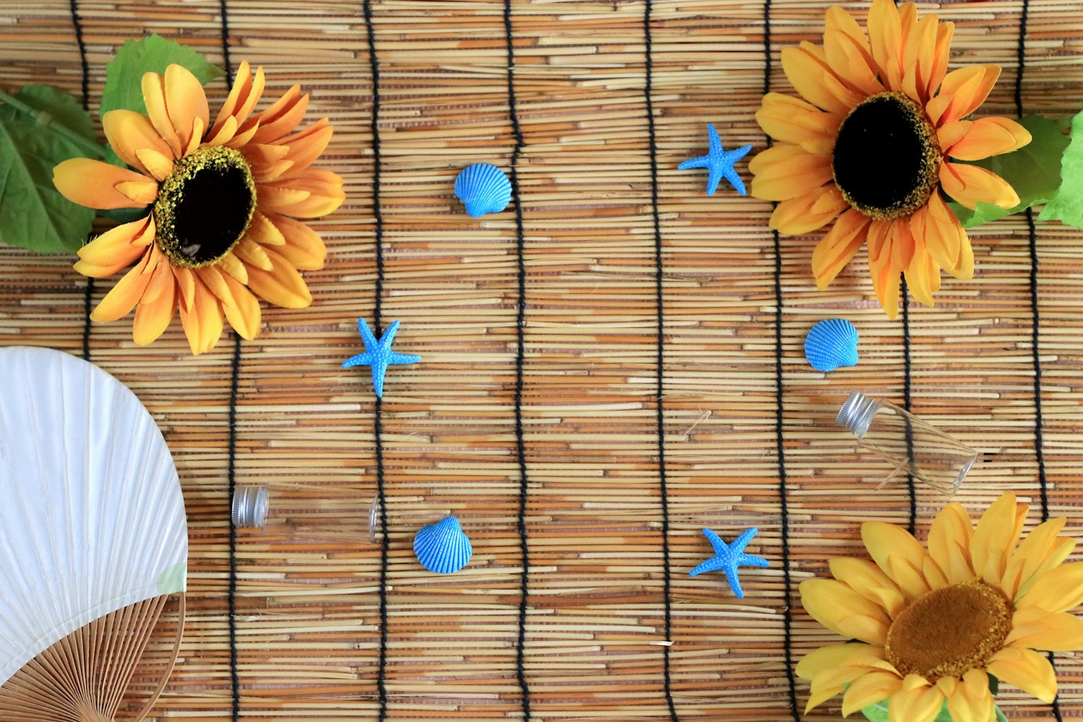 Sunflowers and blue star decorations arranged on straw mat