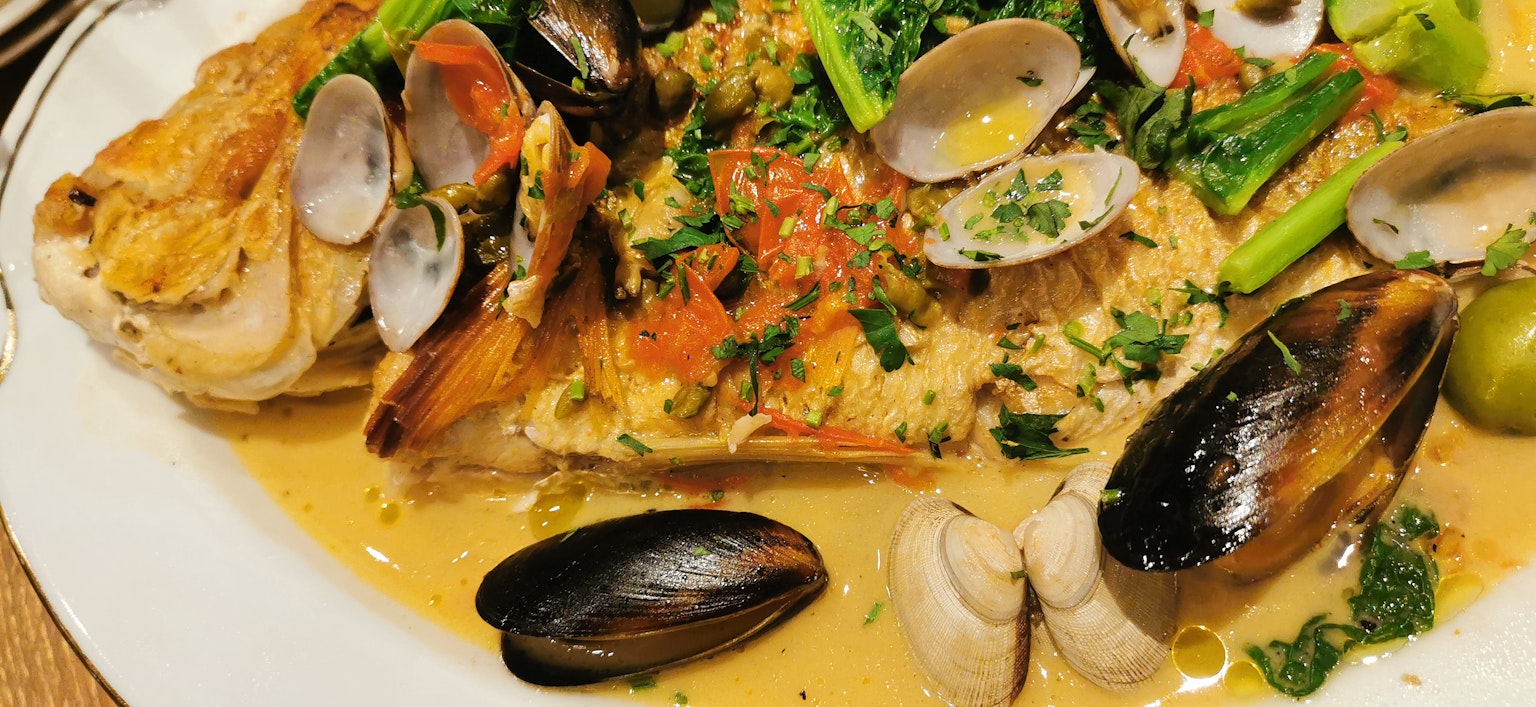 Plato de pescado delicioso adornado con mariscos y hierbas