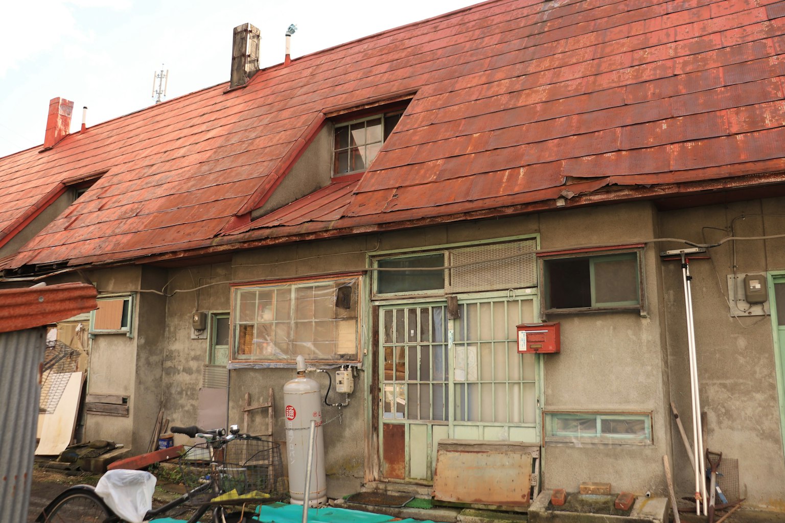 Vista esterna di una vecchia casa con un tetto arrugginito diverse finestre e unità di condizionamento montate