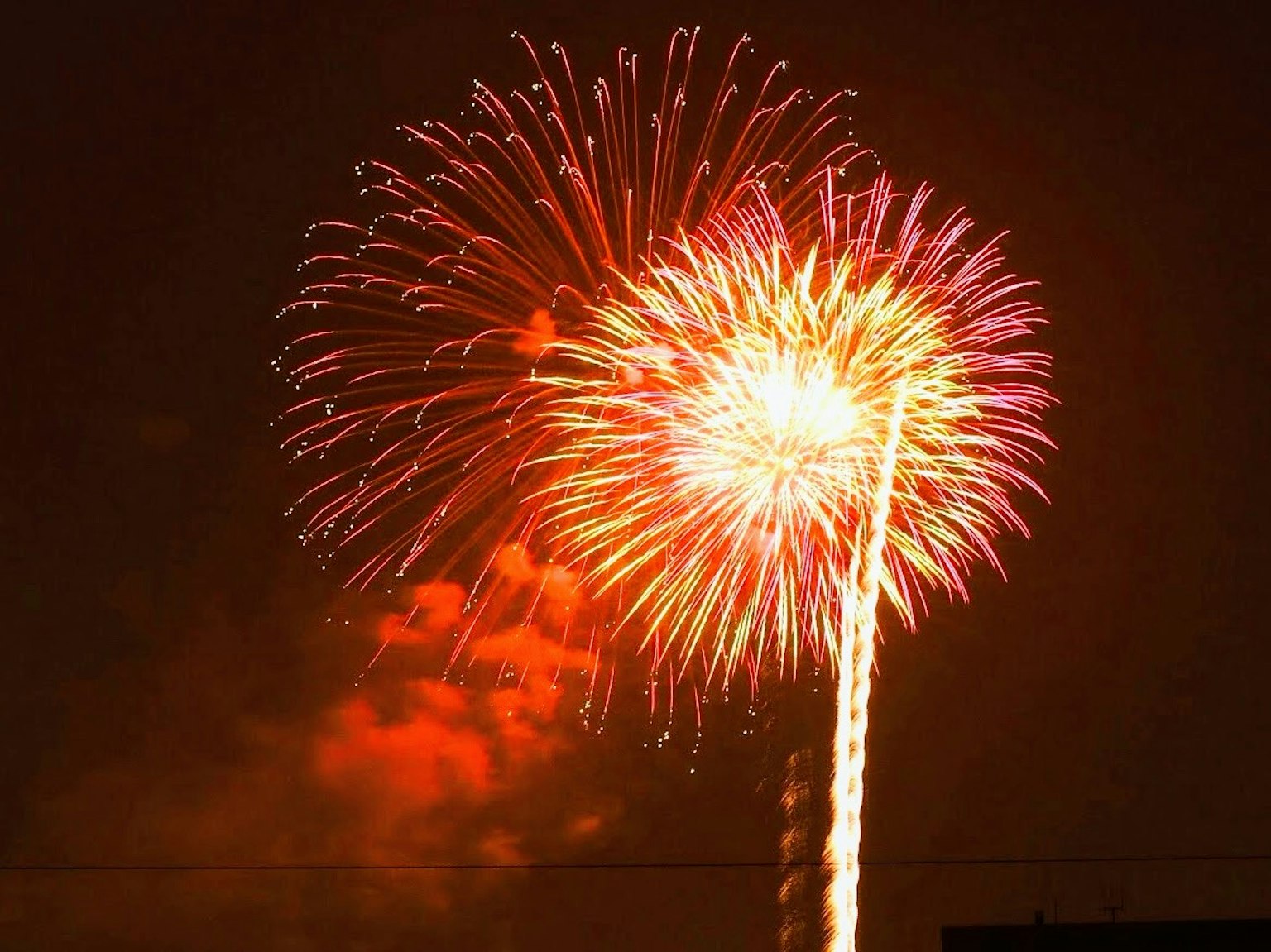 Hermoso momento de fuegos artificiales rojos y naranjas estallando en el cielo nocturno