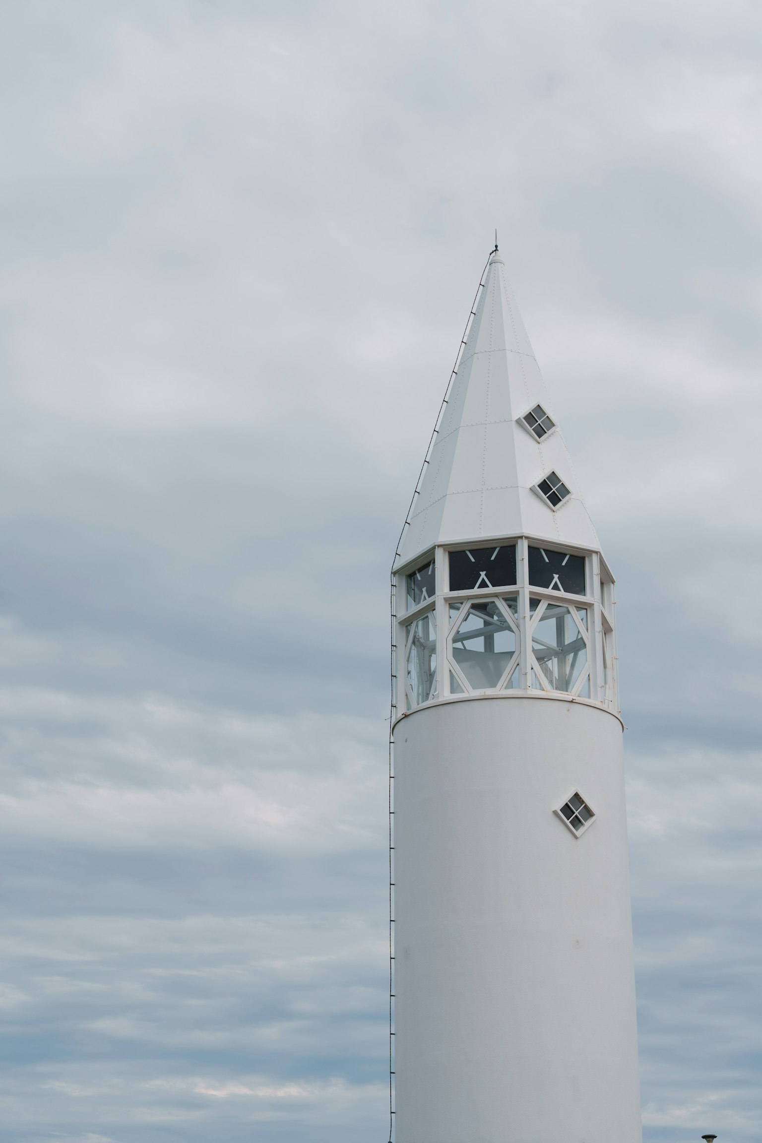 Ein weißer Spitzenturm steht unter einem bewölkten Himmel