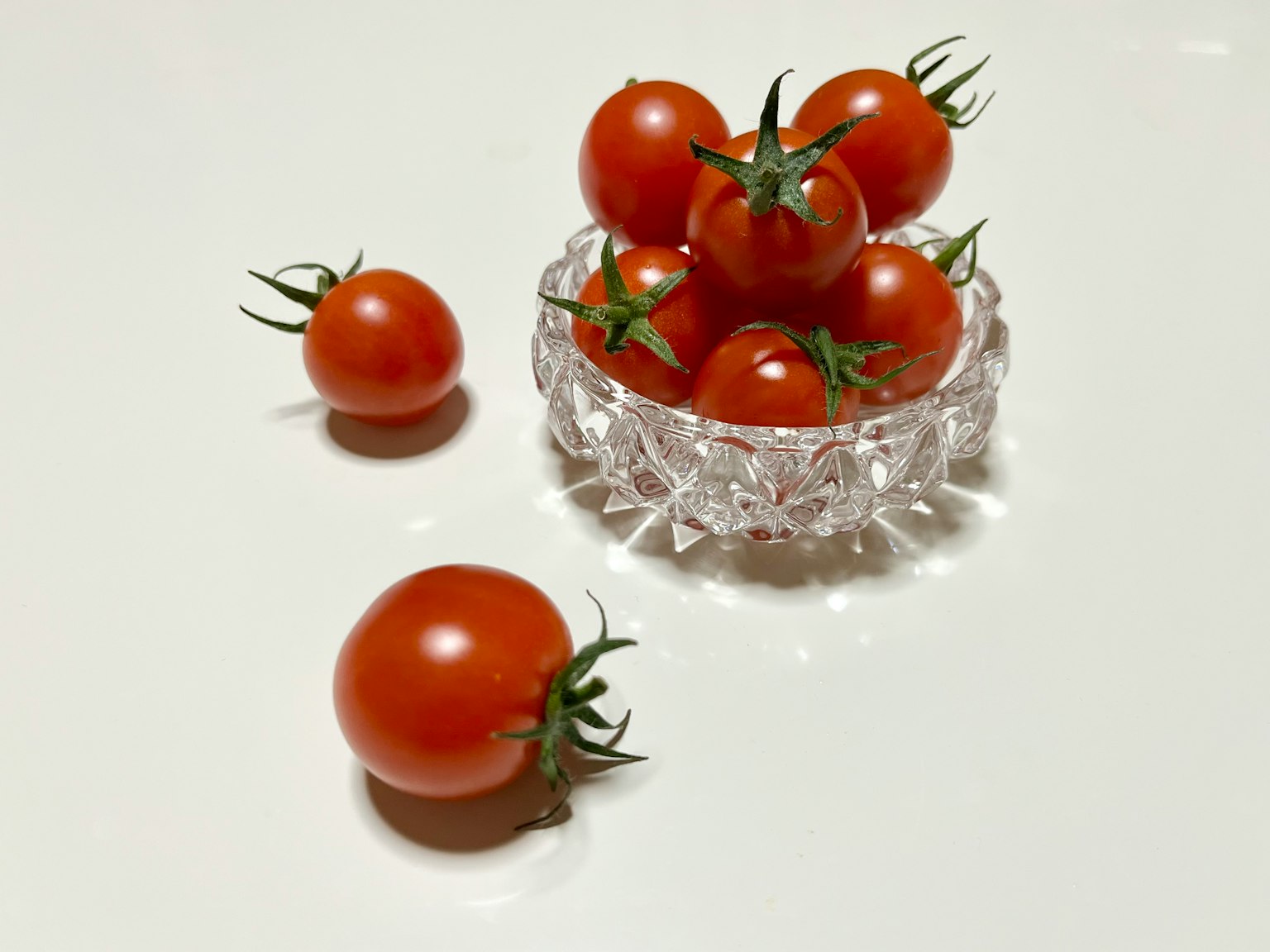 Un grupo de pequeños tomates rojos en un tazón transparente