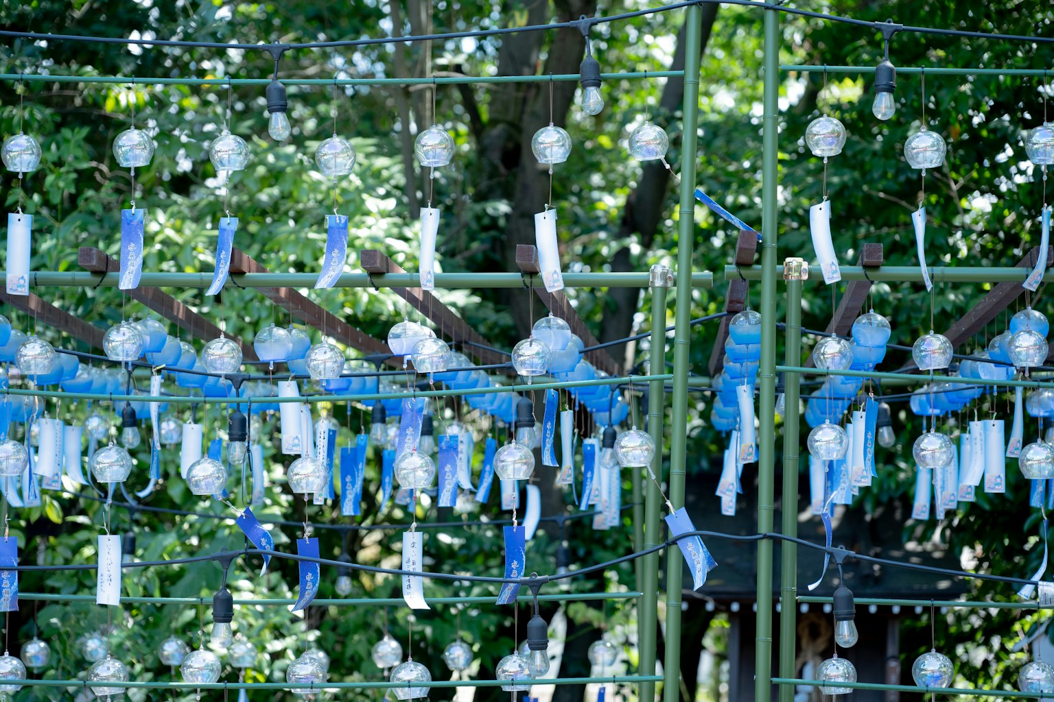 Photo d'une structure en bambou ornée de carillons en verre bleus et de rubans blancs