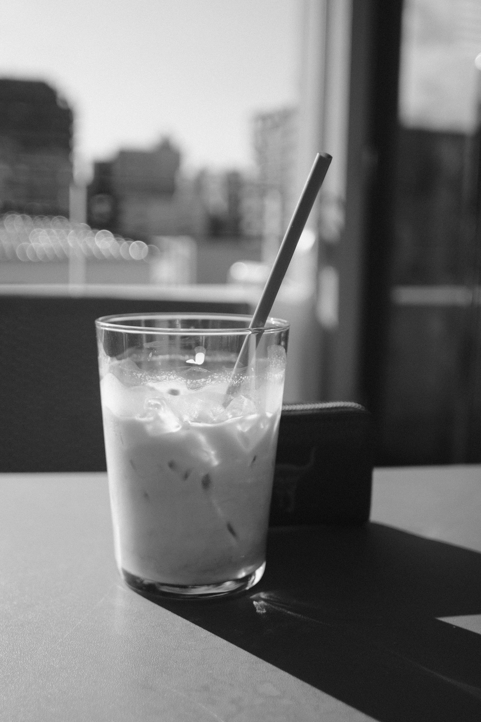 Gambar hitam putih gelas dengan minuman dan sedotan di atas meja