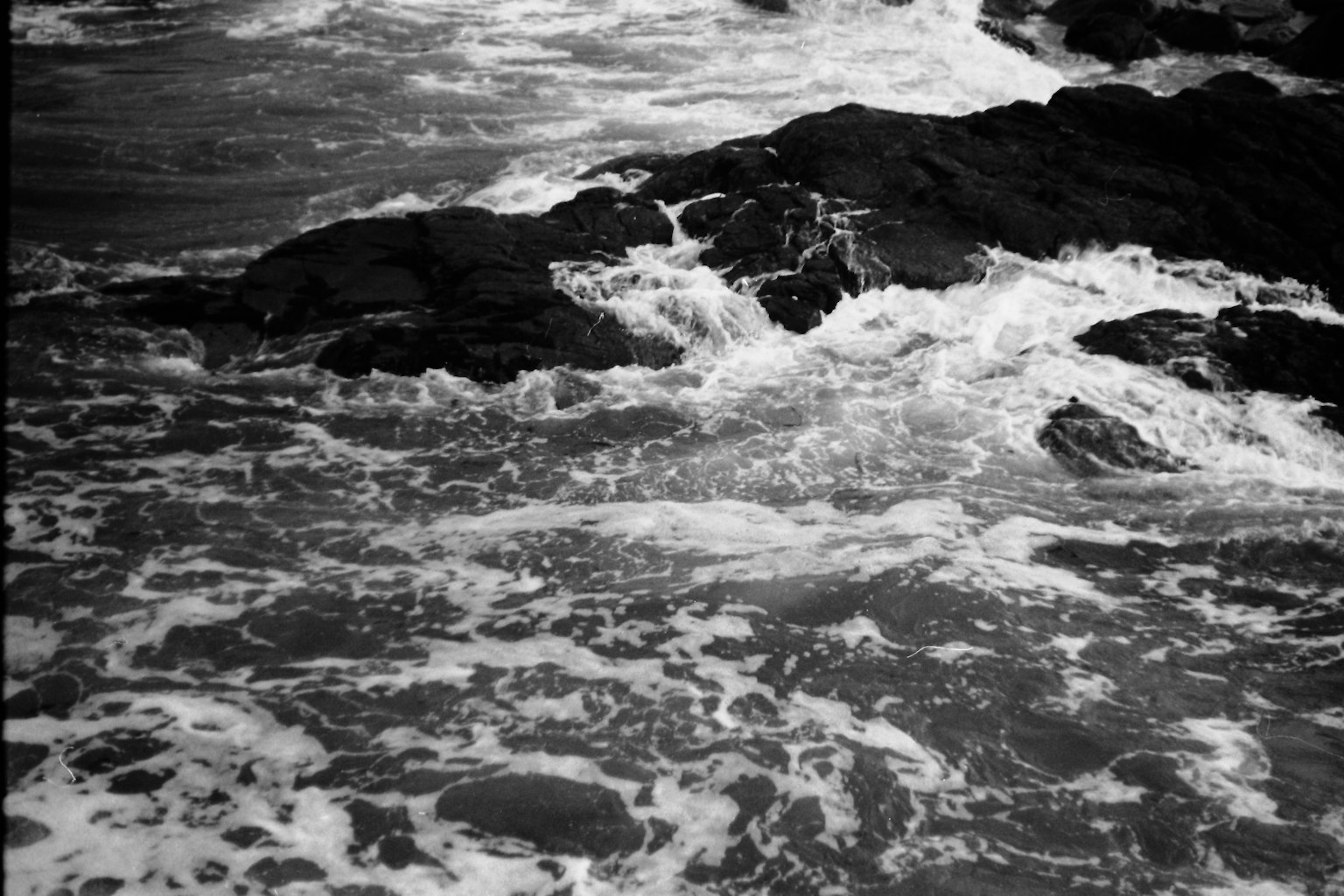 Black and white seascape with waves crashing against rocks