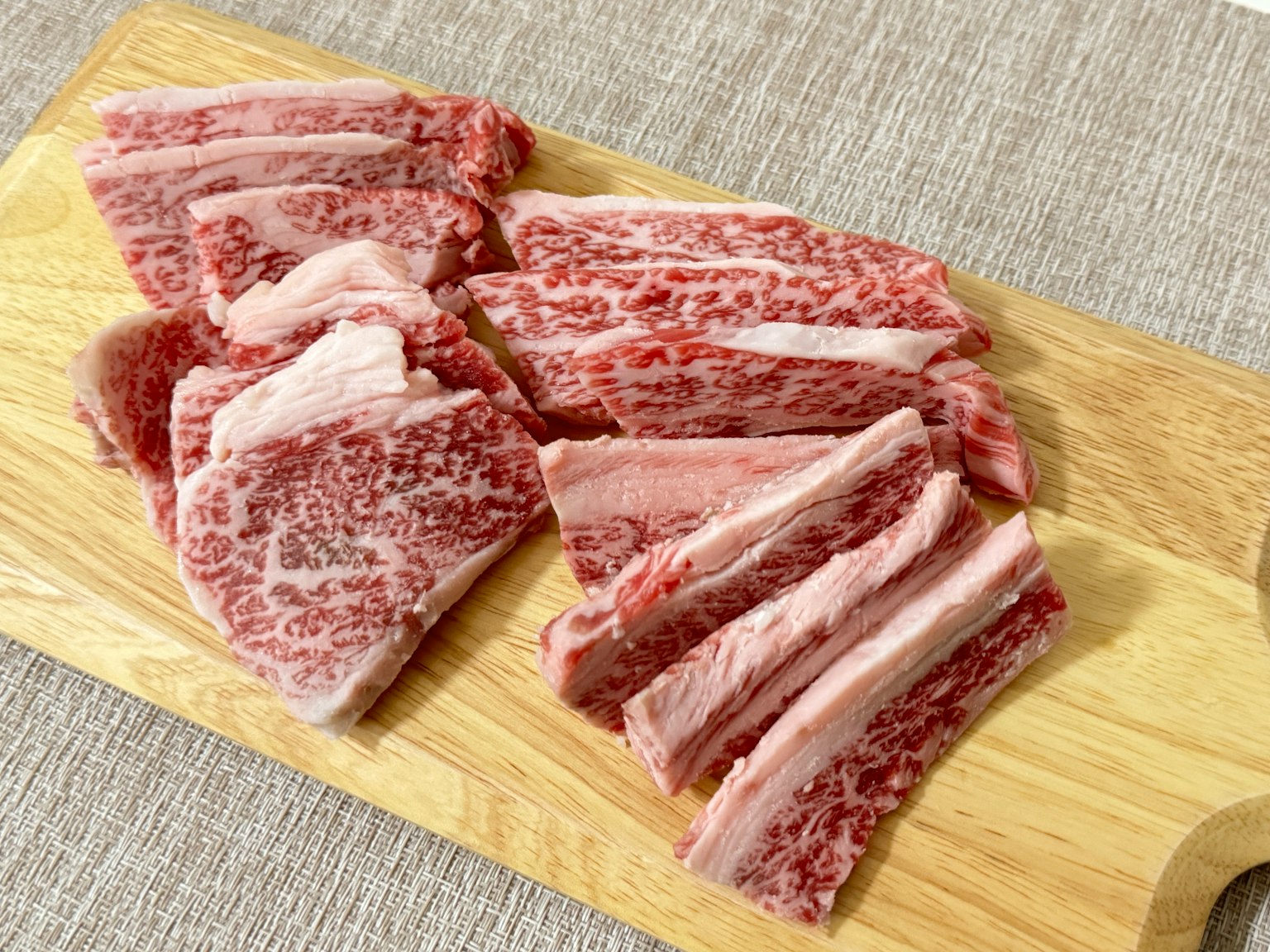 Irisan daging wagyu marmer disusun di atas papan pemotong kayu