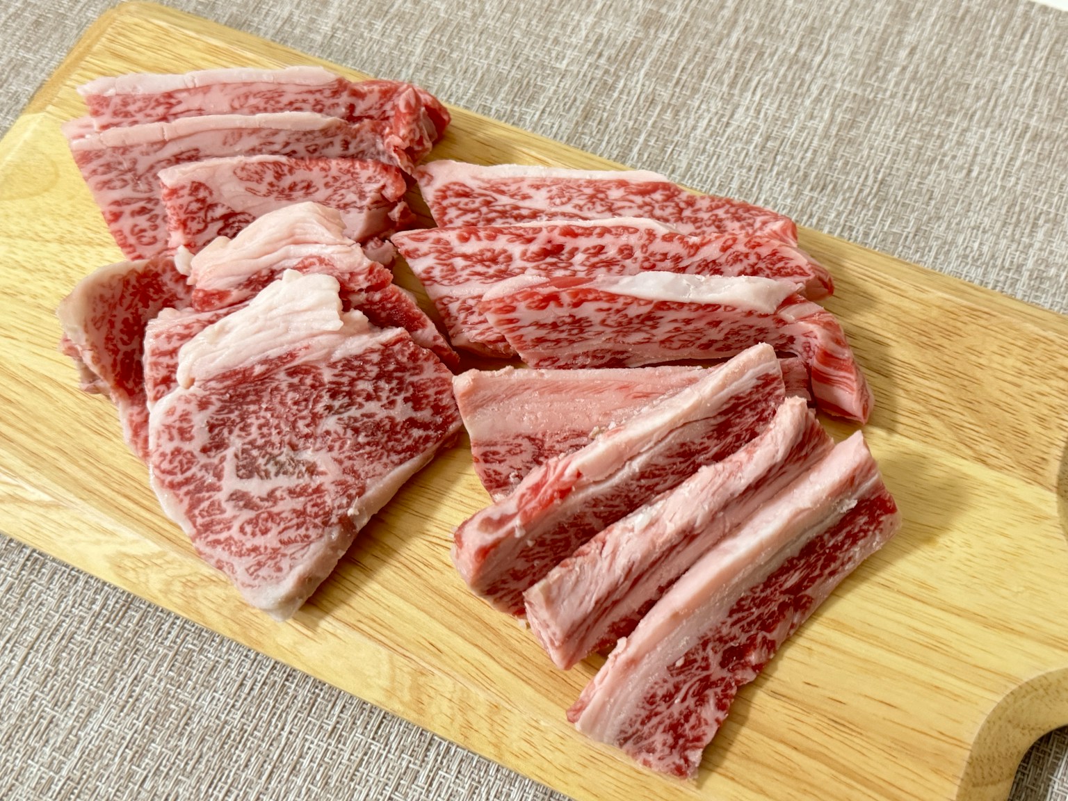 Rebanadas de carne de res wagyu veteada dispuestas sobre una tabla de madera