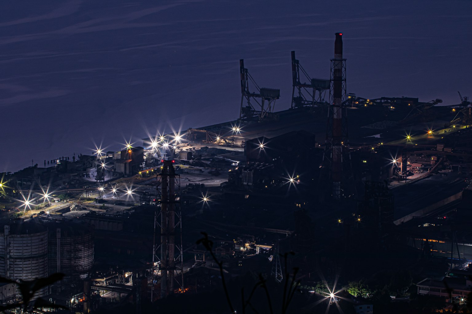 Vista notturna di un'area industriale con fabbriche illuminate e camini