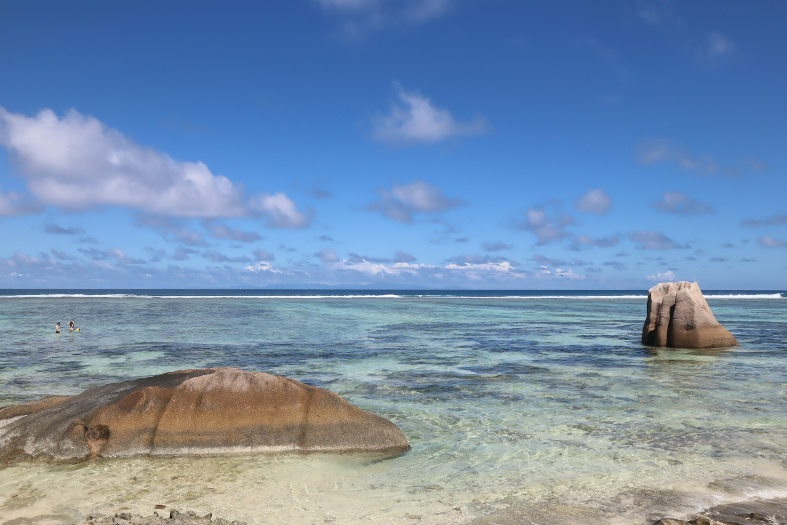 Pemandangan indah laut biru dan langit dengan batu besar di air dangkal